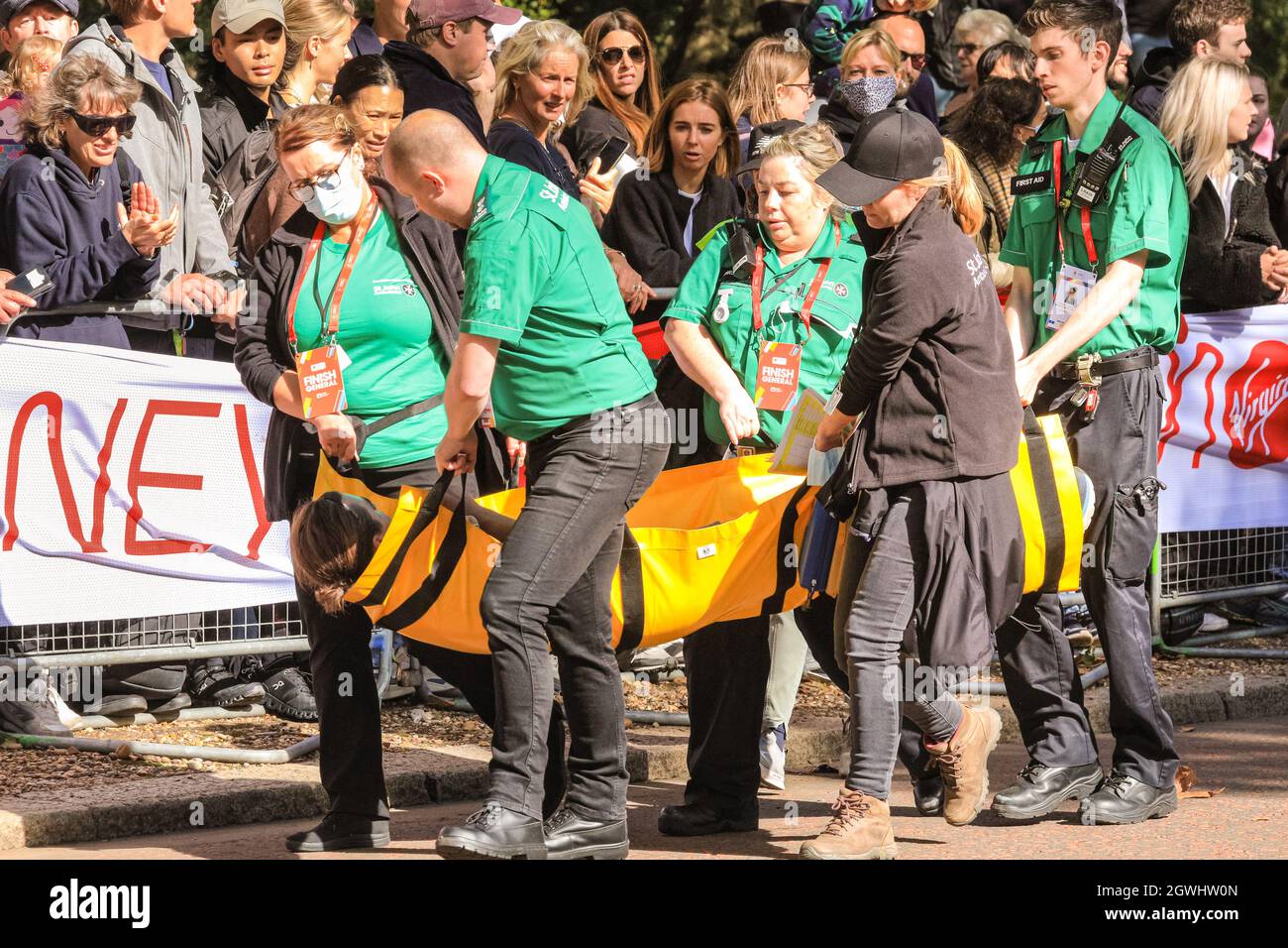 London, Großbritannien. Oktober 2021. Einem eingestürzten Läufer wird auf der letzten Meile beim Birdcage Walk von Sanitätern geholfen. Nach einer 2-jährigen Abwesenheit kehrt der Virgin Money London Marathon zu seinem traditionellen Kurs von Blackheath zur Mall zurück. Mit über 40,000 Teilnehmern und einer ähnlichen Zahl, die gleichzeitig den virtuellen Marathon auf einer Strecke ihrer Wahl absolvieren wird es der größte Marathon überhaupt sein. Kredit: Imageplotter/Alamy Live Nachrichten Stockfoto