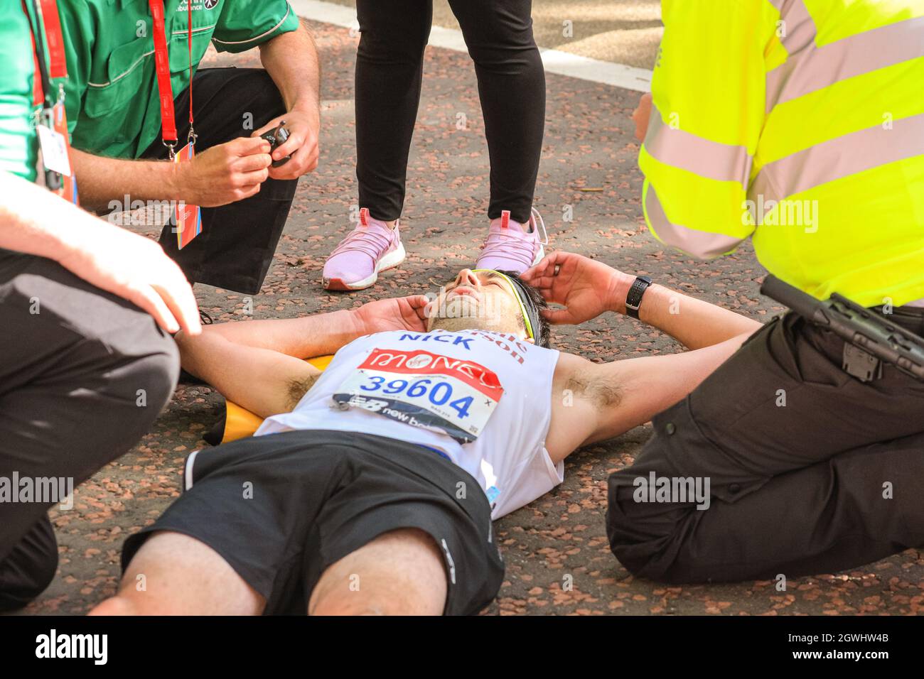 London, Großbritannien. Oktober 2021. Auf der letzten Meile beim Birdcage Walk wird einem eingestürzten Läufer von Polizei und Sanitätern geholfen. Nach einer 2-jährigen Abwesenheit kehrt der Virgin Money London Marathon zu seinem traditionellen Kurs von Blackheath zur Mall zurück. Mit über 40,000 Teilnehmern und einer ähnlichen Zahl, die gleichzeitig den virtuellen Marathon auf einer Strecke ihrer Wahl absolvieren wird es der größte Marathon überhaupt sein. Kredit: Imageplotter/Alamy Live Nachrichten Stockfoto