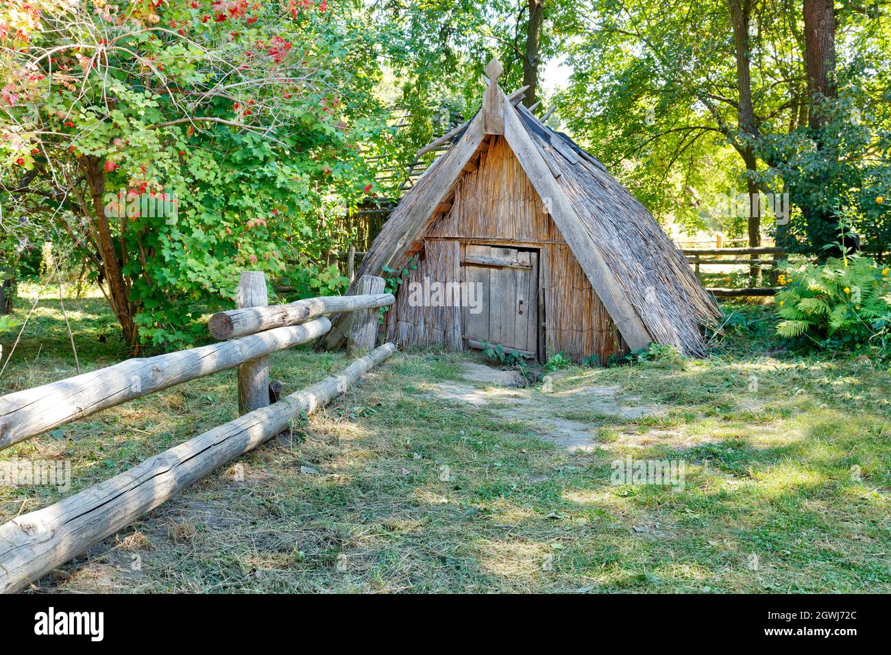 Ein alter, mit Schilf bedeckter Keller und ein Strohdach im Sommergarten eines Landguts. Stockfoto