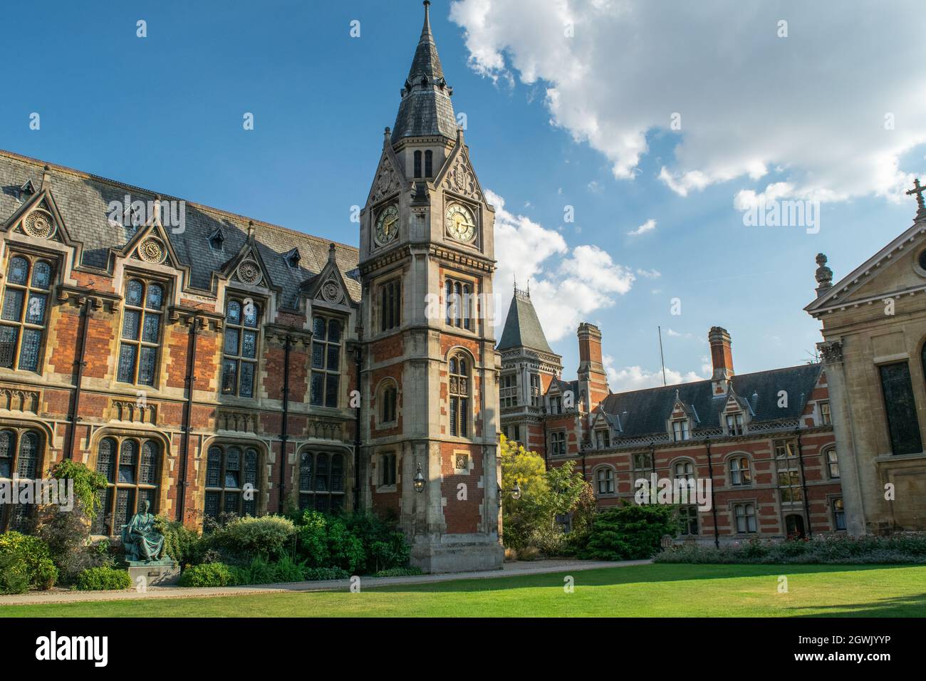 Blick auf das historische gemauerte Christ's College-Gebäude, das an einen mittelalterlichen Uhrenturm vor Rasen und Bänken in Cambridge, England, angeschlossen ist Stockfoto