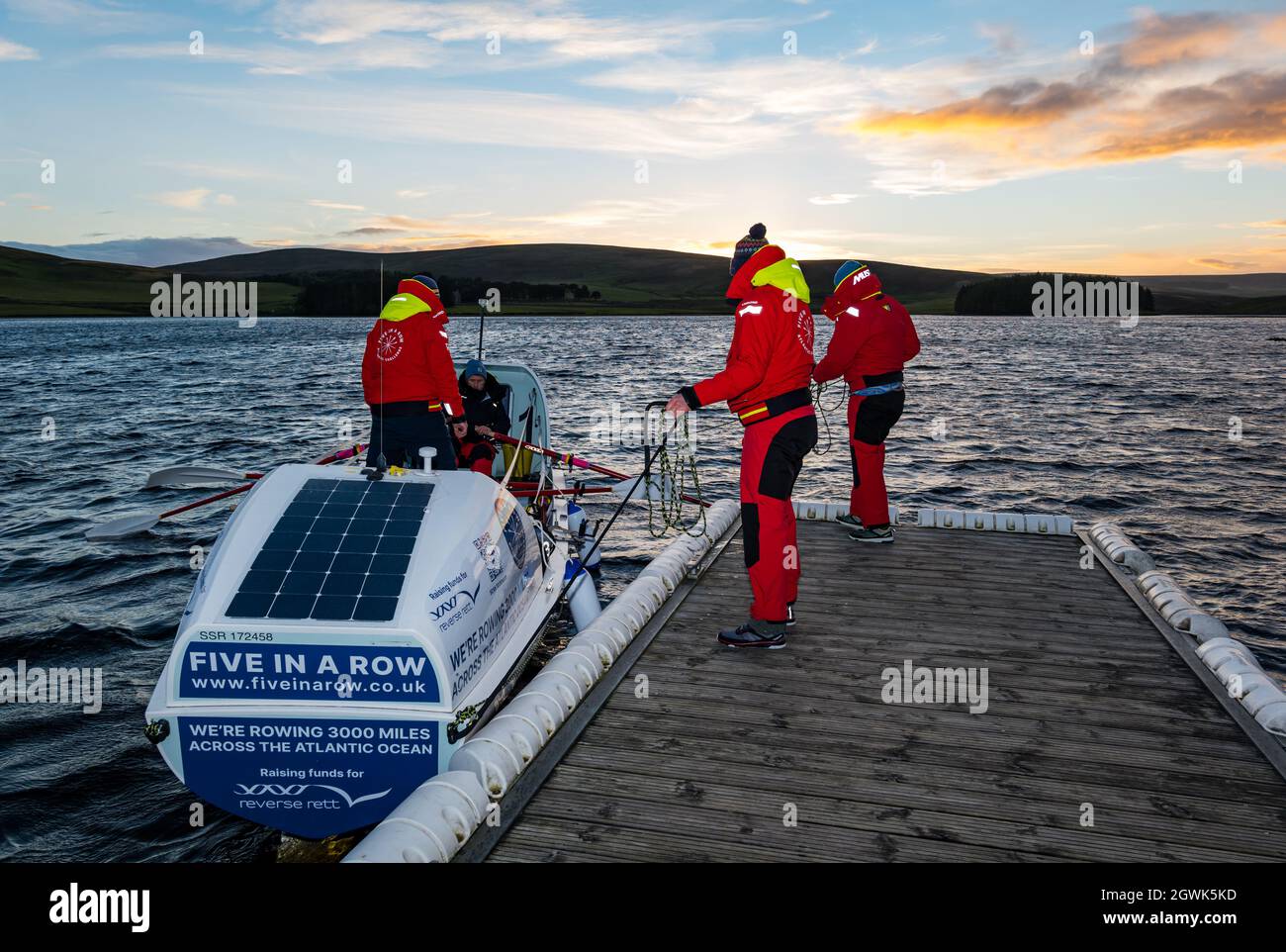 Männer starten ein Ruderboot auf dem Whitesadder Reservoir für ein Training für Atlantic Challenge, East Lothian, Schottland, Großbritannien Stockfoto
