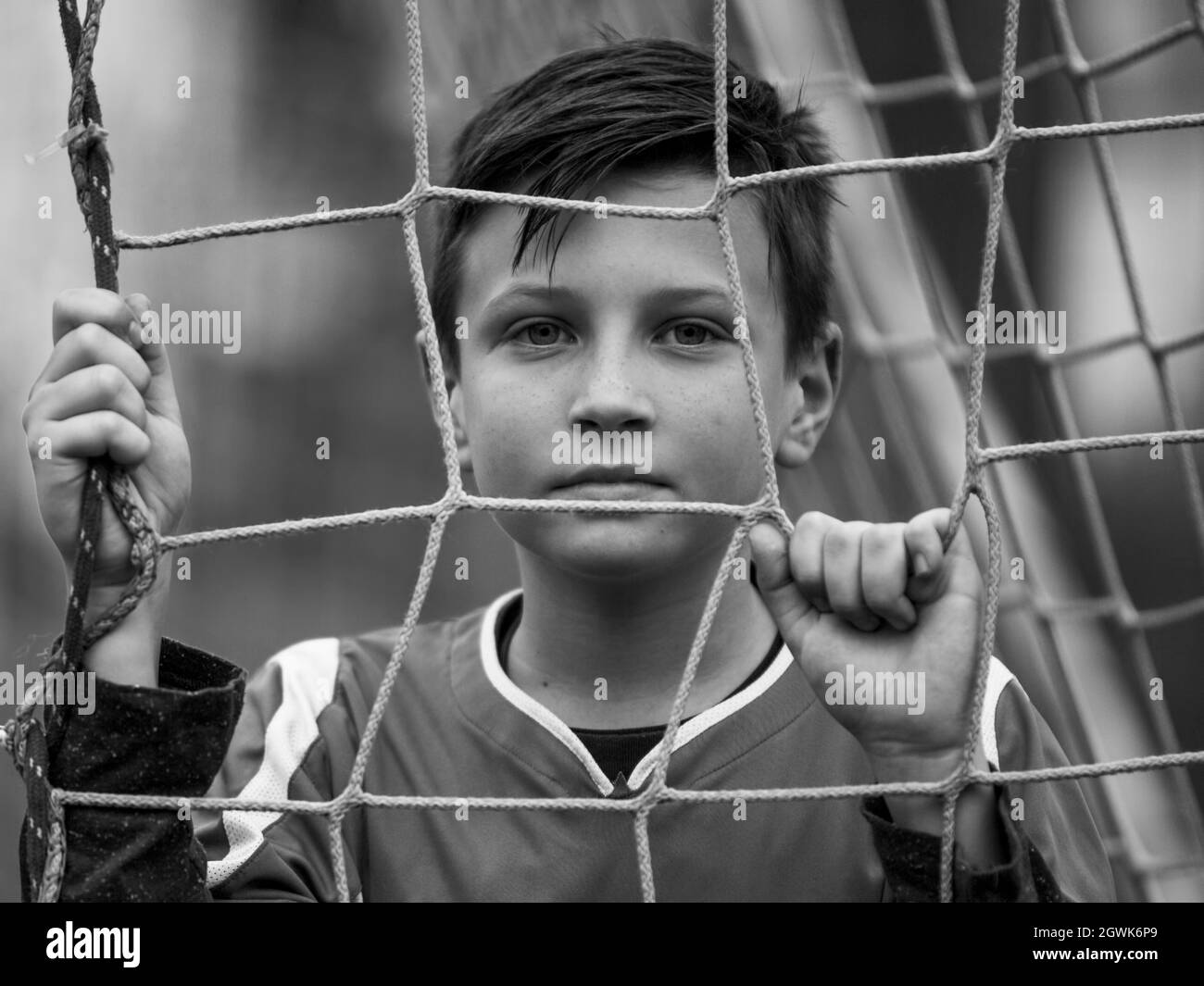 Kleiner Fußballspieler in der Nähe der Tore des Stadions, schwarz-weißes Porträt. Stockfoto