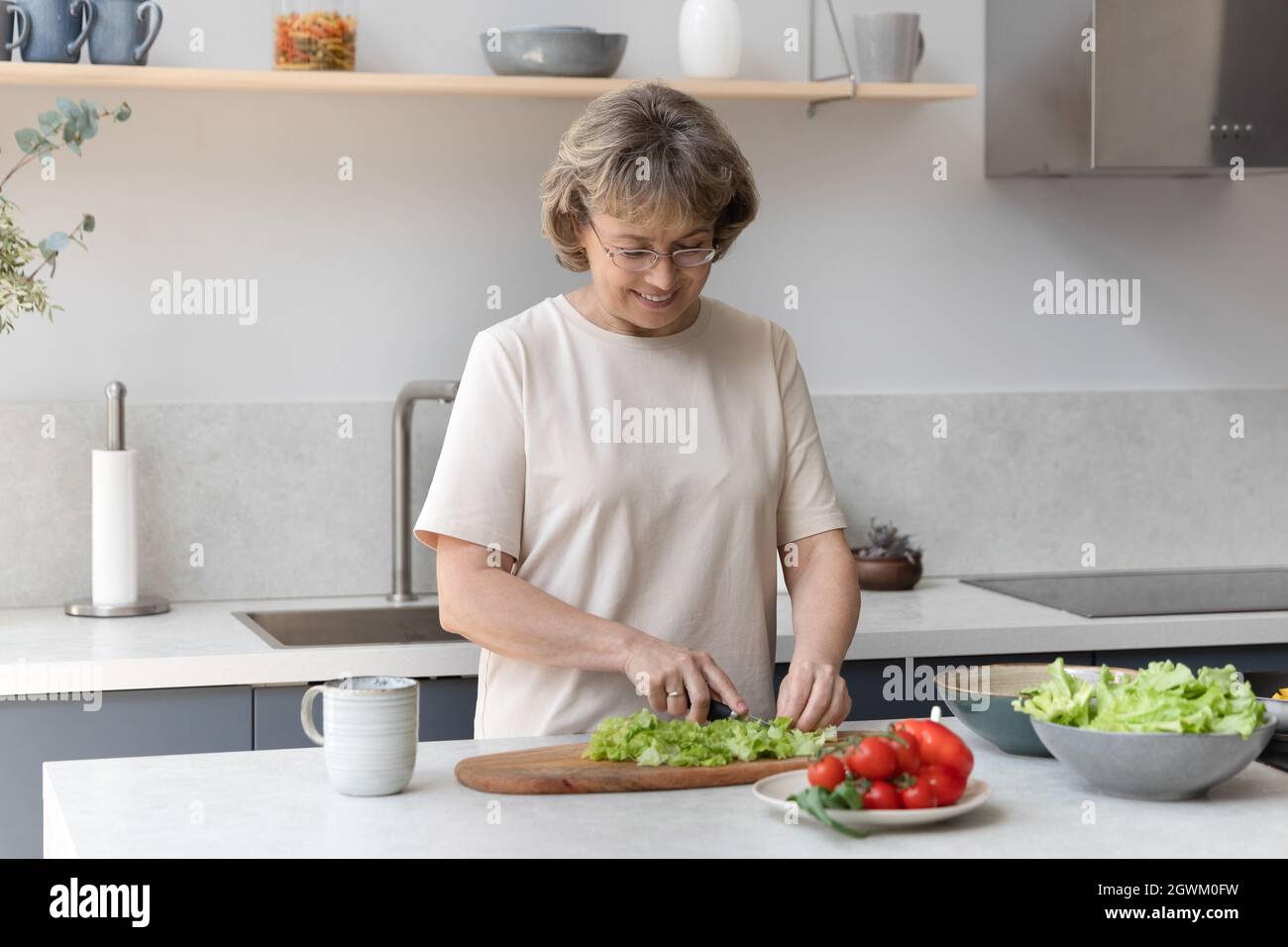 Glückliche, schöne Frau mittleren Alters, die Essen zubereitete. Stockfoto