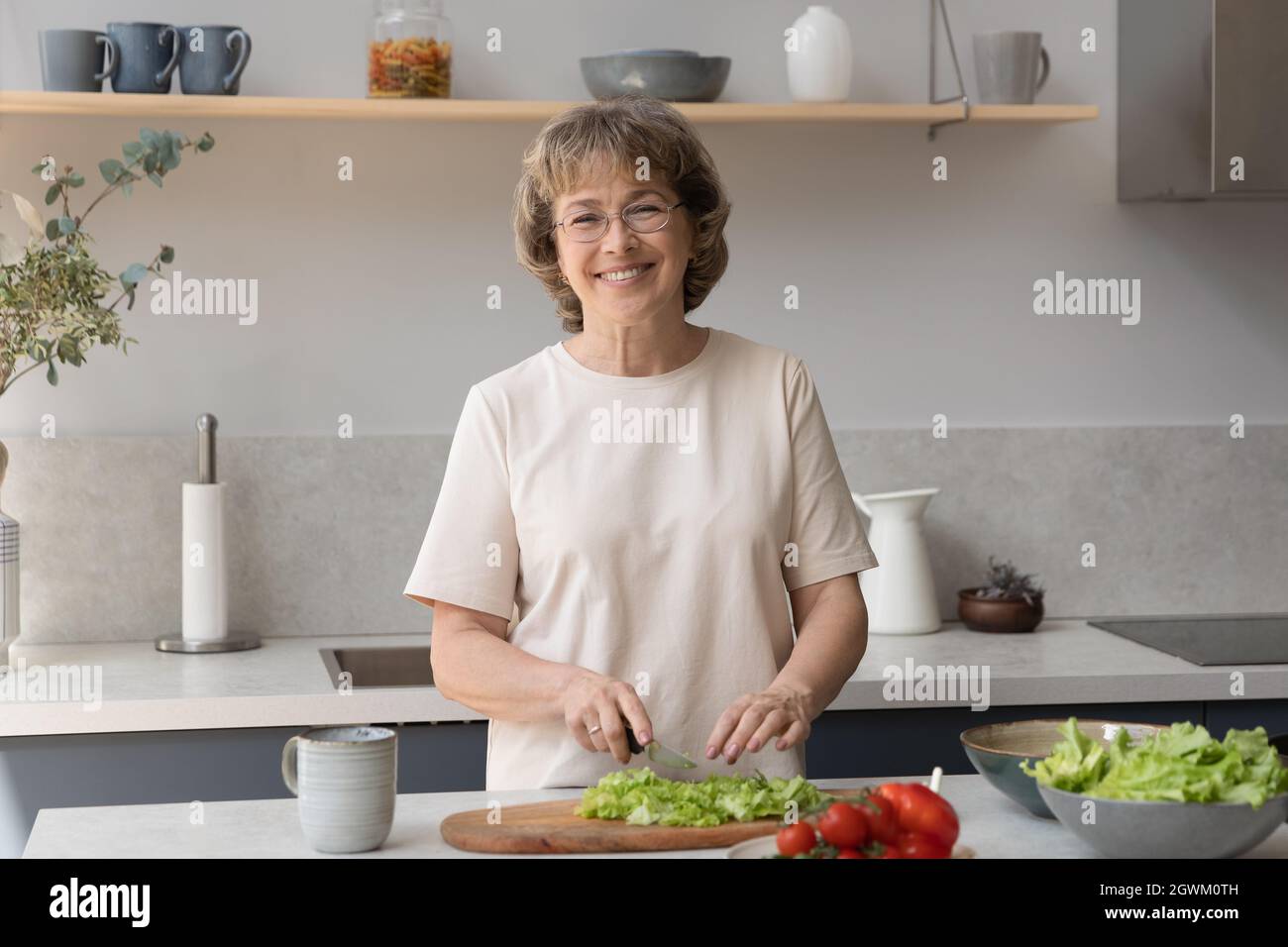 Porträt einer lächelnden älteren Frau, die zu Hause Essen zubereitete. Stockfoto