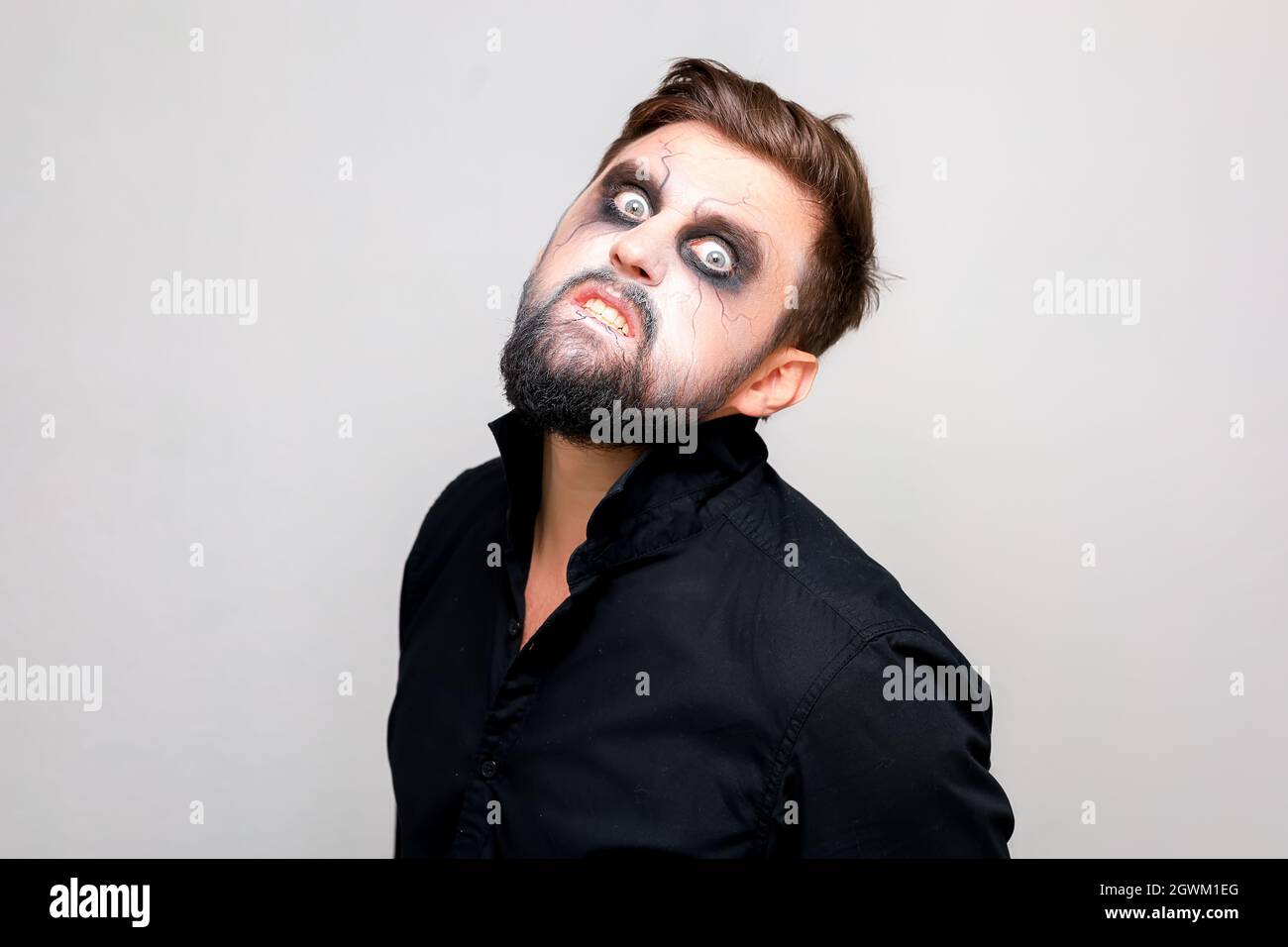 Ein bärtiger Mann mit Untoten-Make-up an Halloween schaut mit großen Augen auf die Kamera Stockfoto