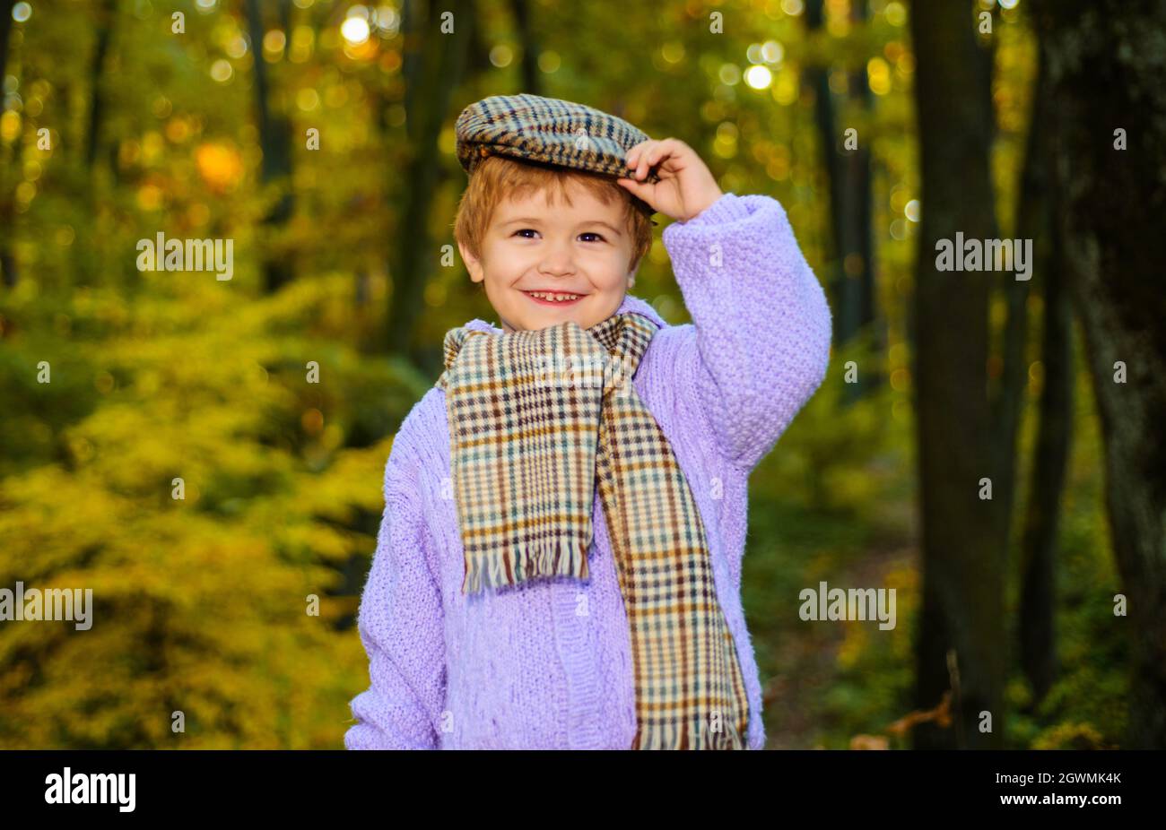 Glückliches Kind im Autumn Park. Niedlicher Junge in warmem Pullover, Hut und Schal. Herbstmode für Kinder. Stockfoto