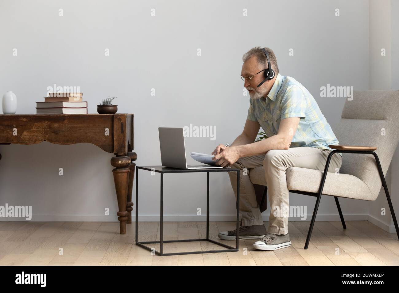 Fokussierter Mann mittleren Alters im Headset, der an Online-Kursen studiert. Stockfoto