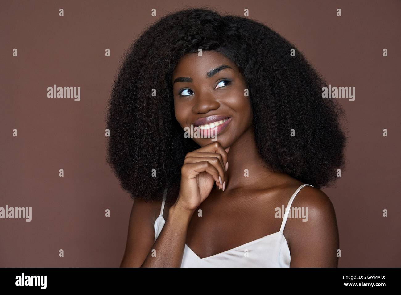 Junge schwarze wunderschöne Mädchen berühren Gesicht isoliert auf braun. Kopfbild im Porträt. Stockfoto