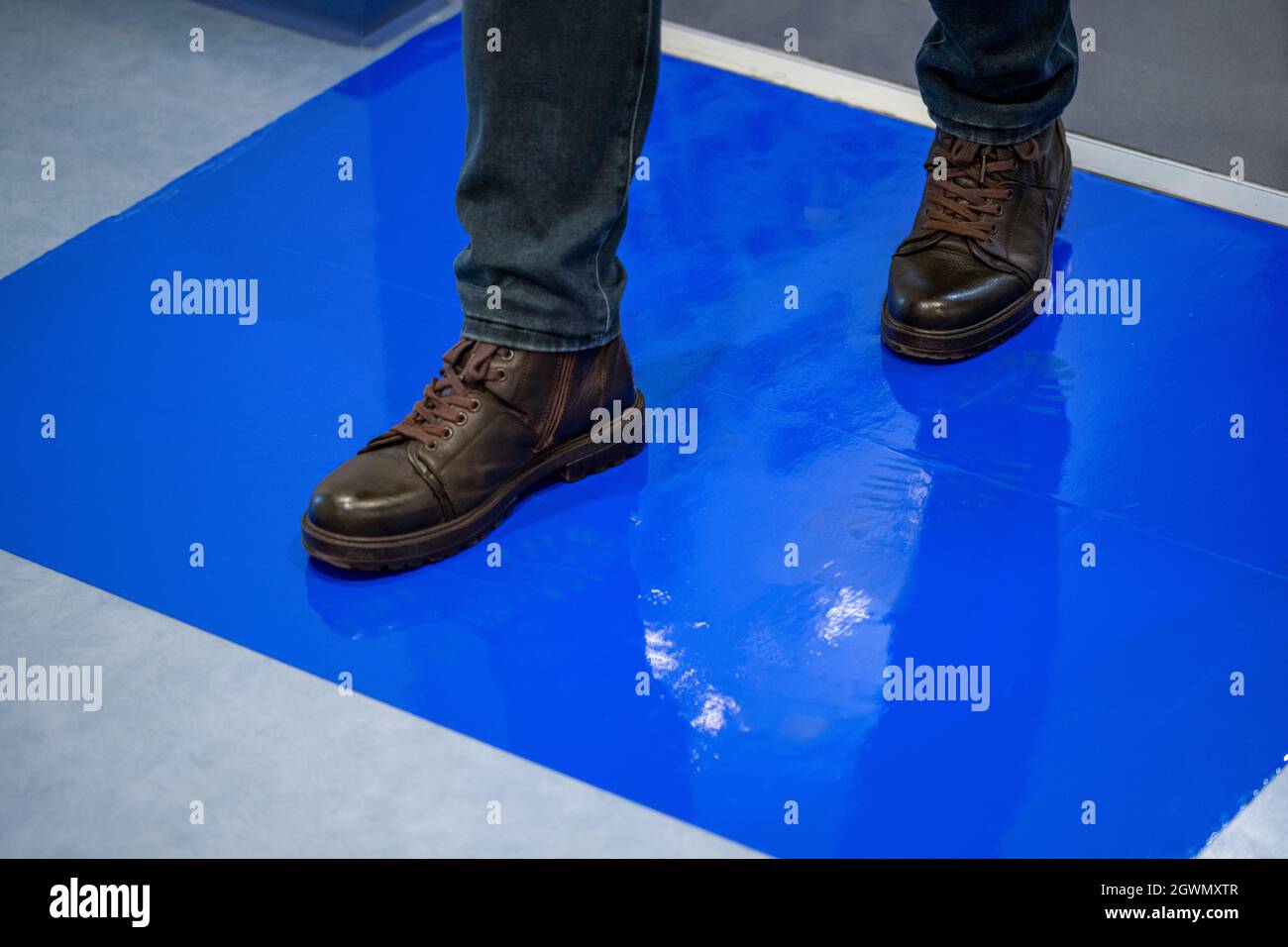 Mann in braunen Schuhen tritt auf blauen Klebstoff klebrige Matten  Stockfotografie - Alamy