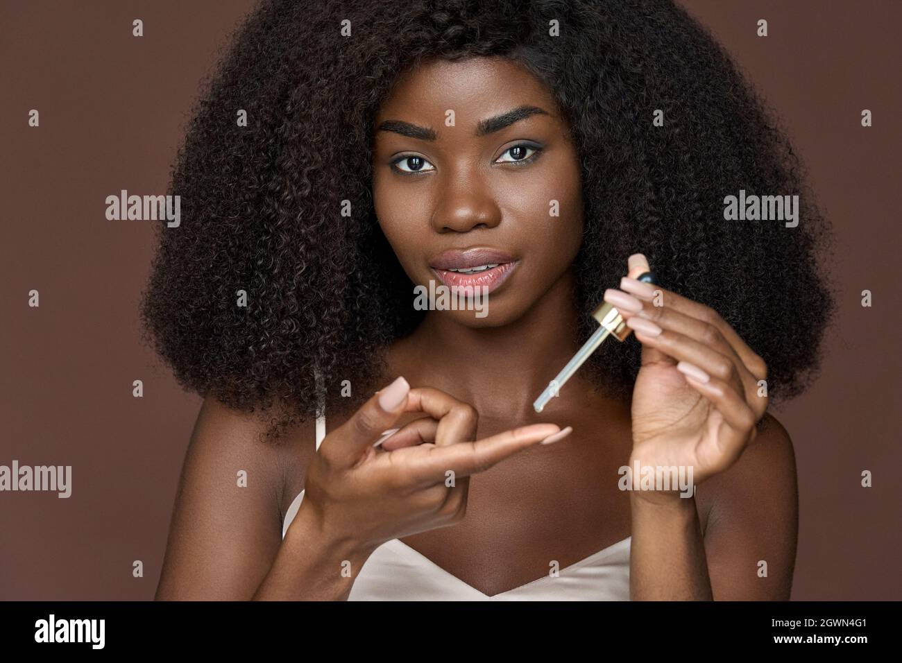 Schöne schwarze Mädchen Anwendung Gesichts-Serum-Öl auf den Finger. Hautpflegekonzept. Stockfoto