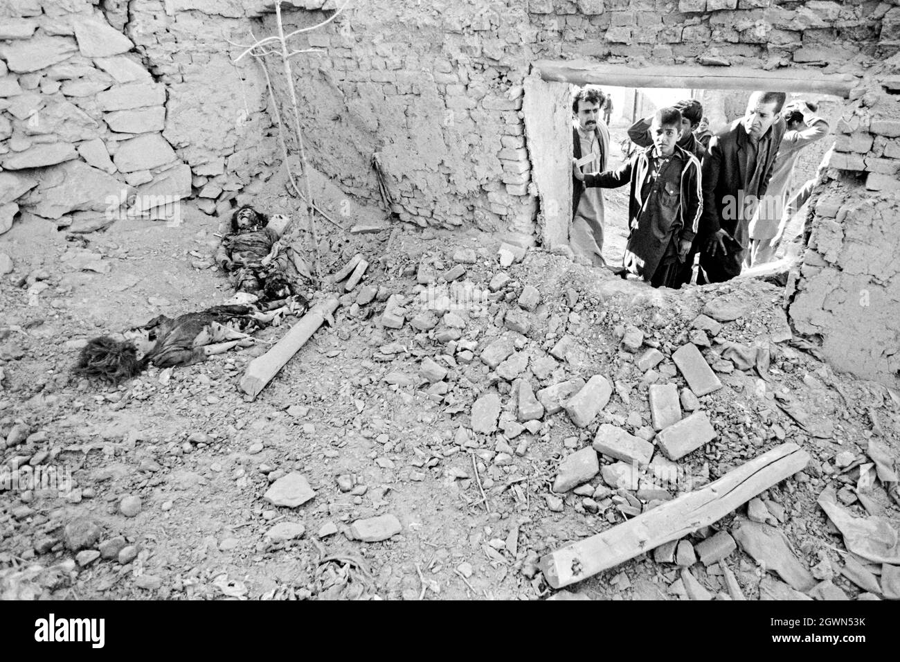 KABUL, AFGHANISTAN. April 1988. Nachbarn blicken entsetzt auf das Gemetzel nach einem Raketenangriff, bei dem zwei junge Mädchen in einem Innenhof im Wohnviertel Karte-ye-Sakhi am 16. April 1988 in Kabul, Afghanistan, ums Leben kamen. Die Rakete, die von den afghanischen Mudschaheddin abgefeuert wurde, traf das Haus und tötete die jungen Mädchen sofort. Stockfoto