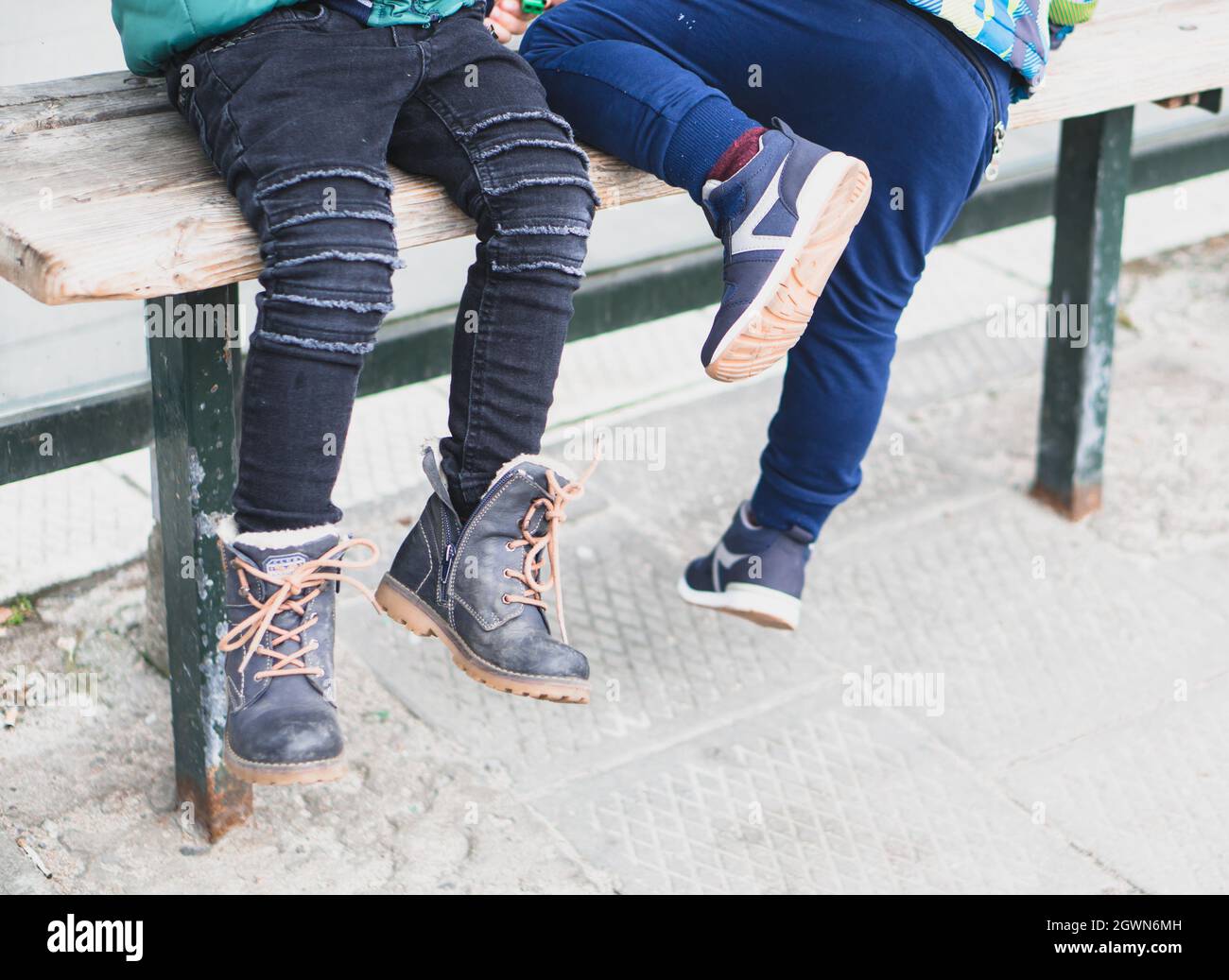 POSEN, POLEN - 24. März 2018: Eine Aufnahme von Kinderbeinen auf einer Holzbank mit Schuhen im Park Stockfoto