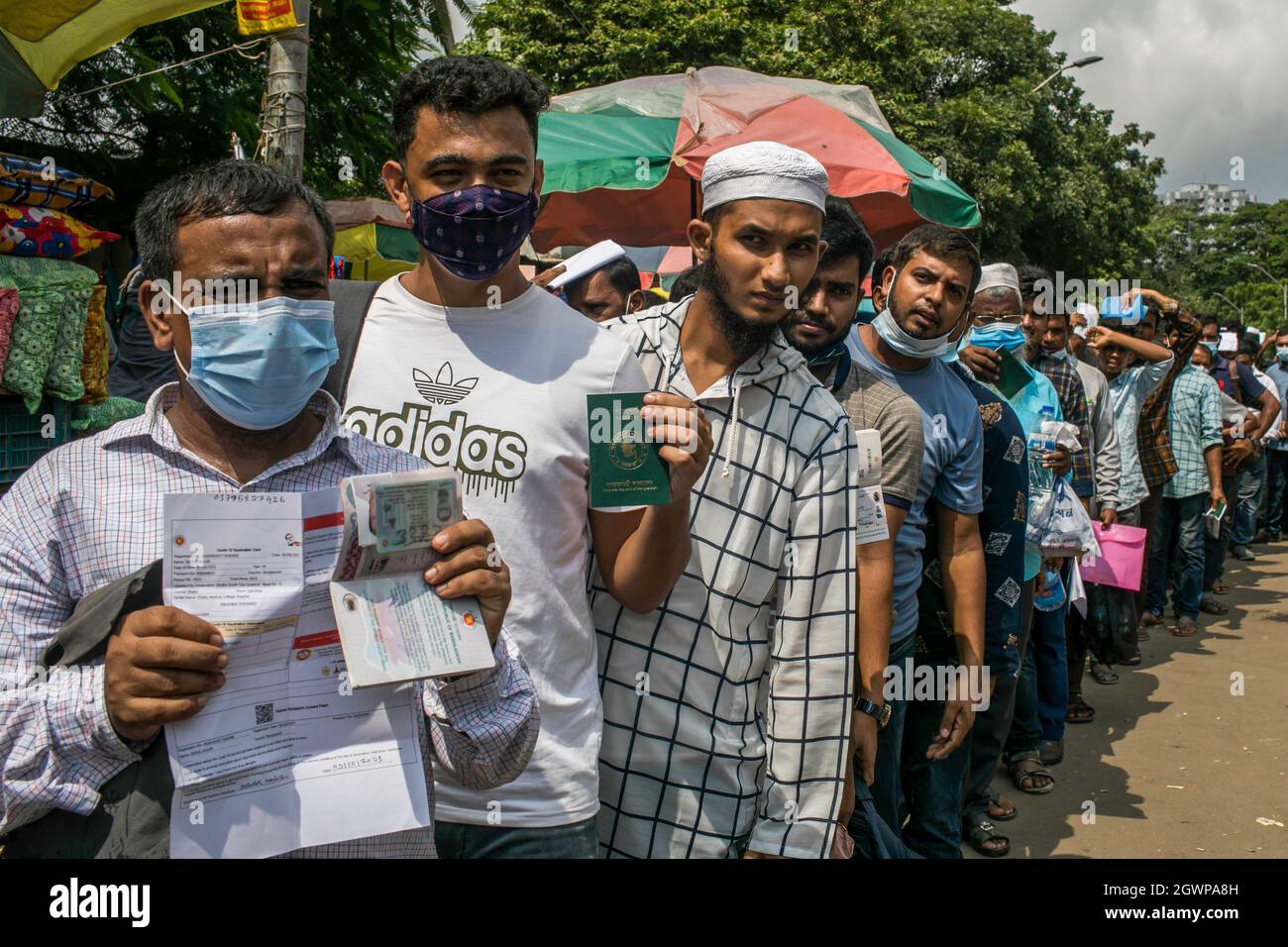 Dhaka, Bangladesch. Oktober 2021. Wanderarbeiter, der in einer Schlange vor dem Dhaka Medical College Hospital steht, zeigt seinen Pass, während er auf die Covid-19-Impfung wartet. Kredit: SOPA Images Limited/Alamy Live Nachrichten Stockfoto