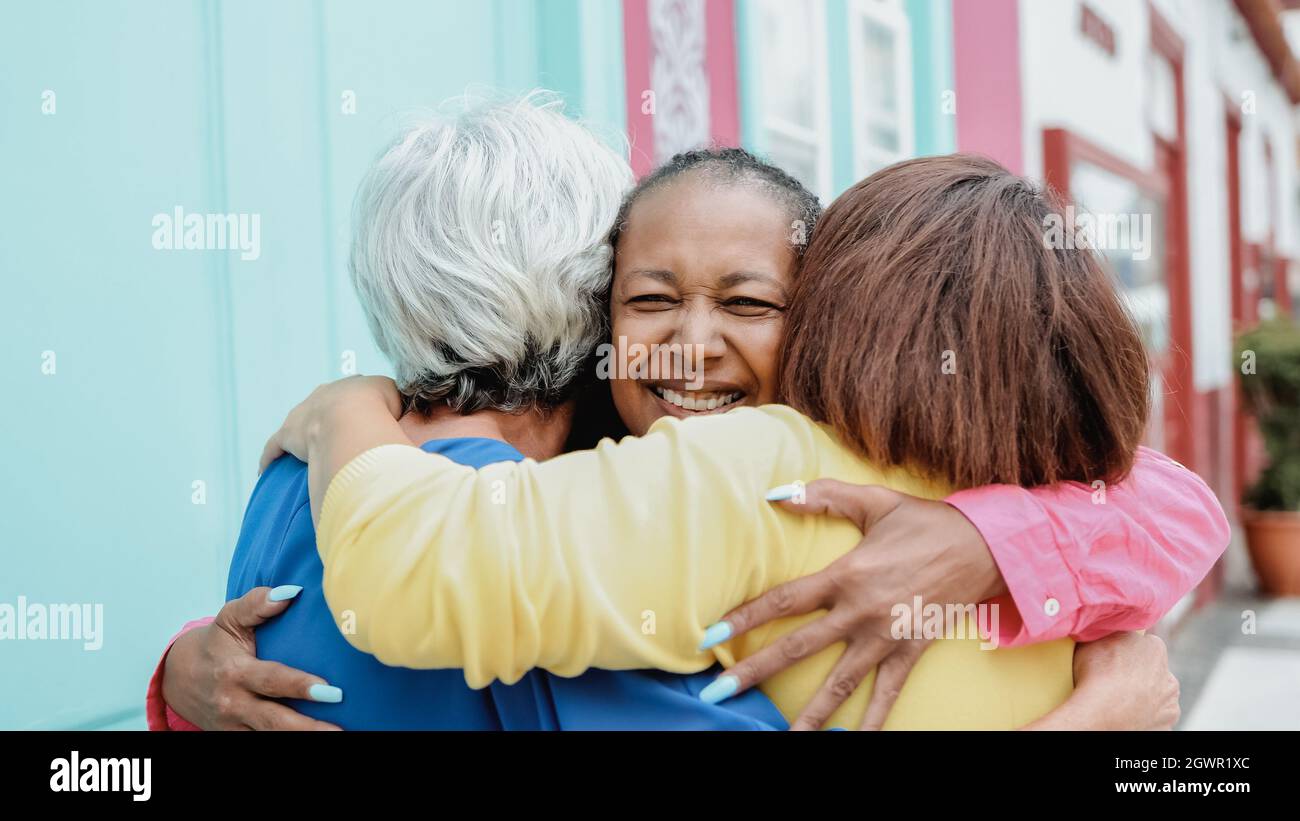 Multirassische ältere Frauen haben Spaß zusammen Umarmung im Freien in der Stadt - Fokus auf afrikanische weibliche Gesicht Stockfoto