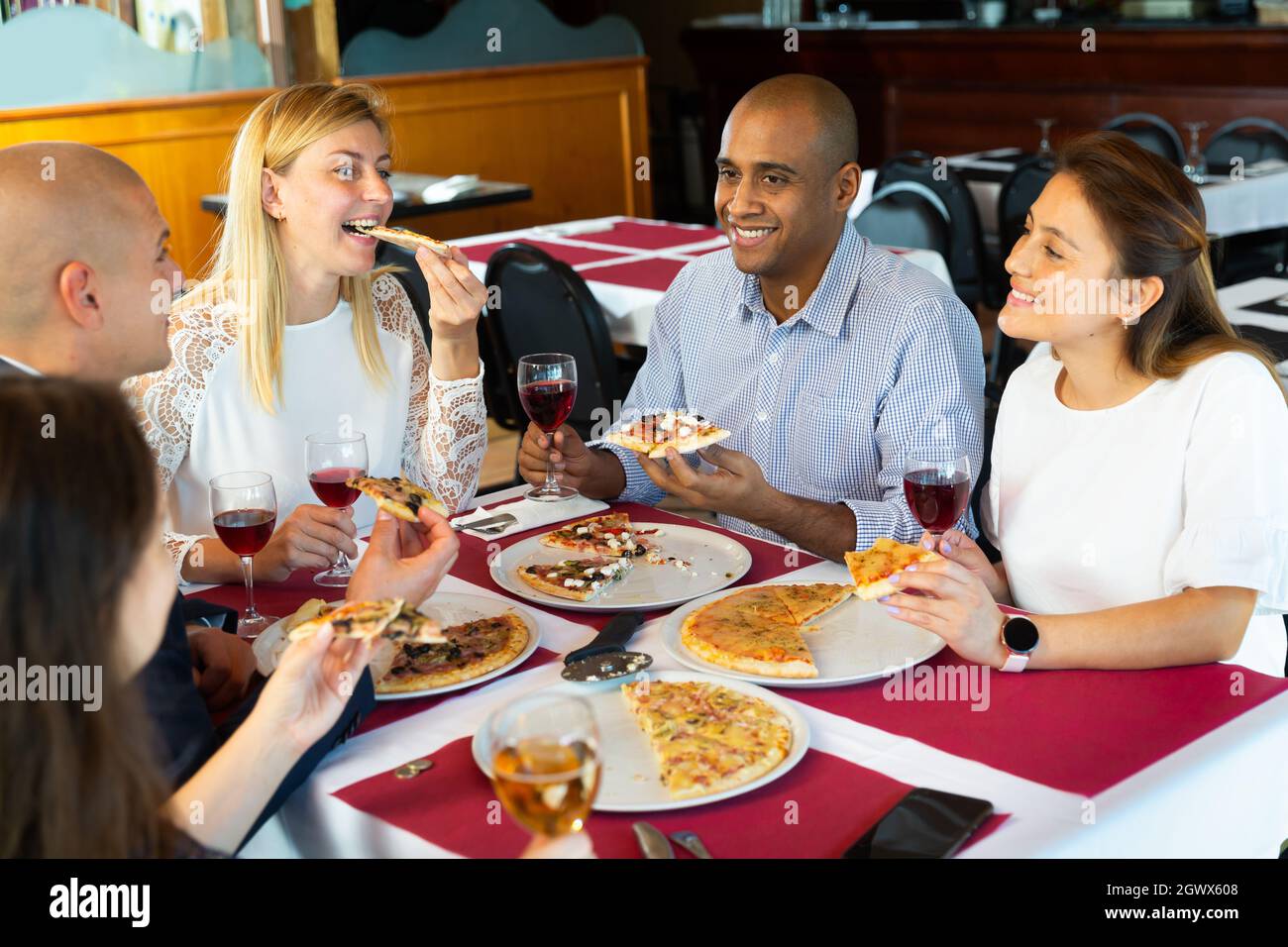 Glückliche Freunde essen leckere Pizza und plaudern miteinander im Restaurant Stockfoto