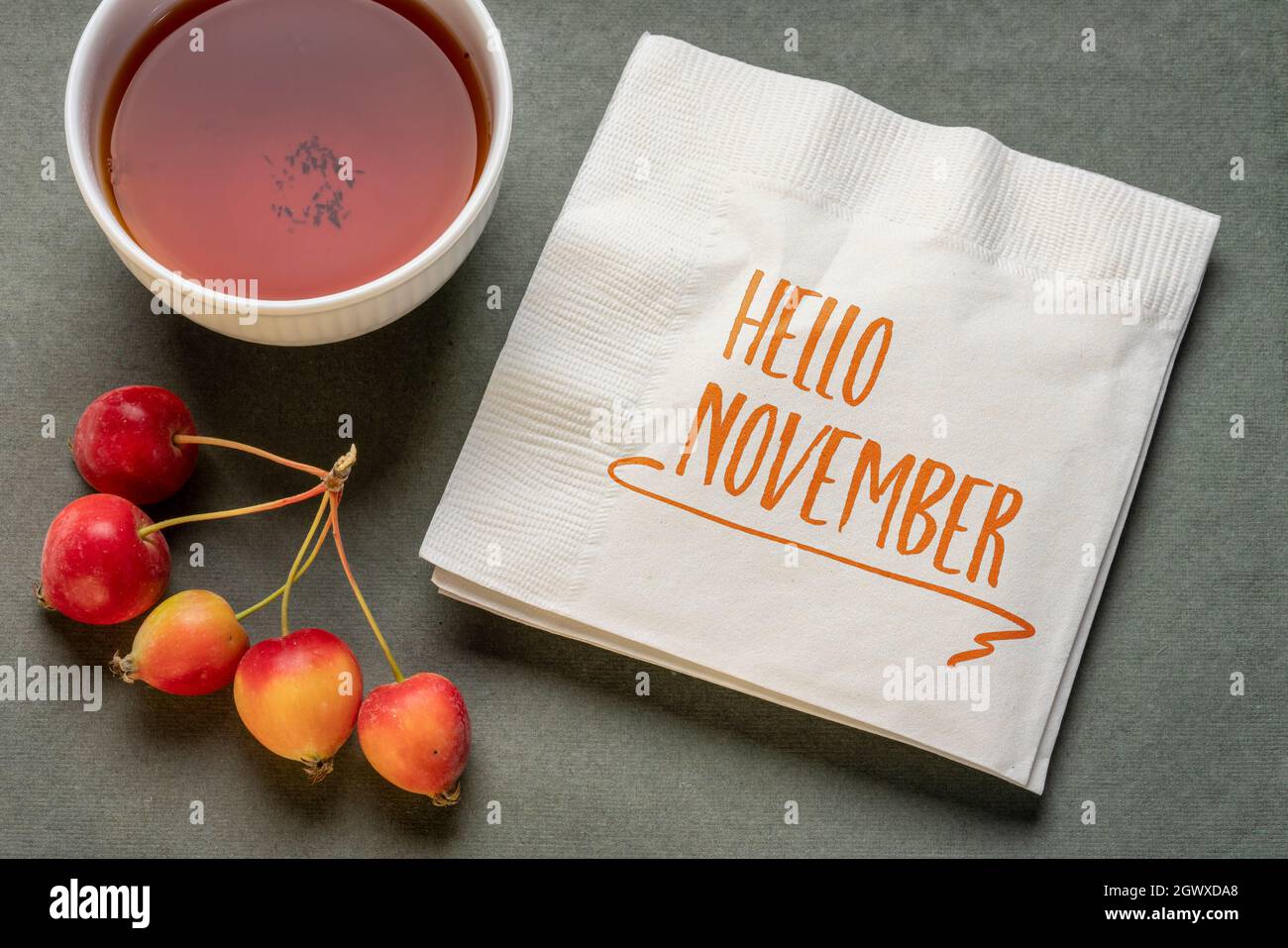 Hallo November Handschrift auf Serviette mit einer Tasse Tee und einem Haufen Krabbenäpfel, saisonal abstrakt Stockfoto