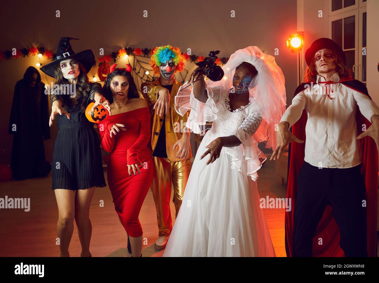 Eine Gruppe von Erwachsenen in gruseligen Kostümen, die wie Zombies auf der Halloween Party spazieren gehen Stockfoto