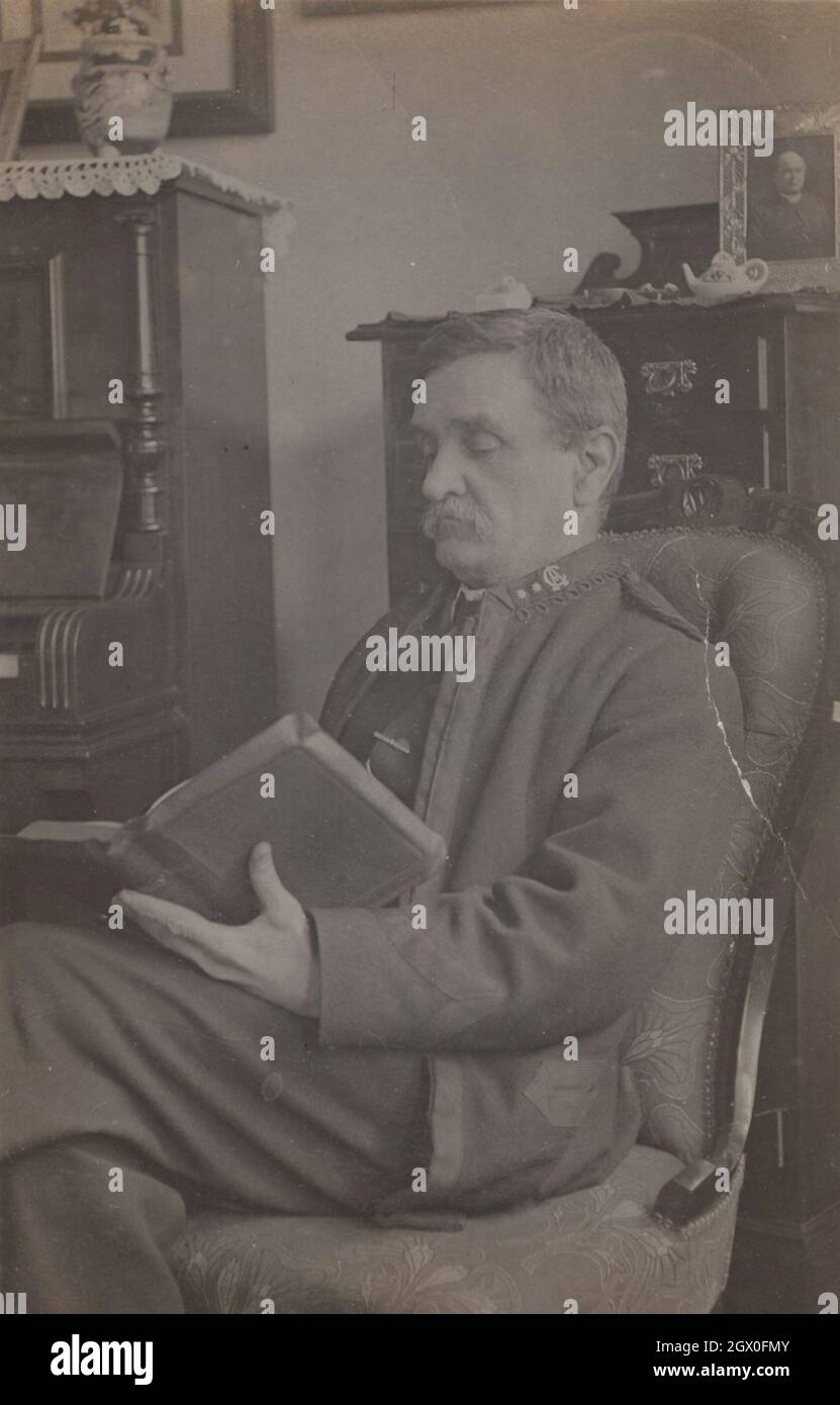 Seltener Moment aus den 1940er Jahren. Der alte britische Militäroffizier (möglicherweise hochrangig) sitzt in seinem bequemen Sessel und liest ein großes Buch. Zeitraum: 1940er Jahre Quelle: Original-Fotokarte. Stockfoto