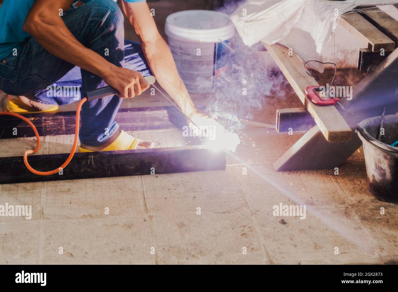 Mann Schweißer, der eine Metalltreppenkonstruktion in einem Wohngebäude mit einer Schweißmaschine macht. Stockfoto