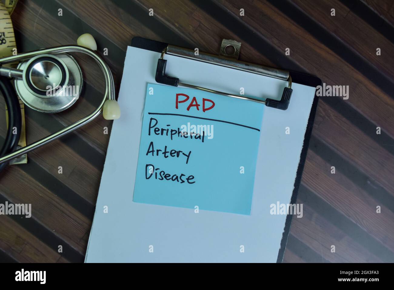 PAD - peripherale Arterienkrankheit Schreiben Sie auf klebrige Notizen isoliert auf Holztisch. Stockfoto
