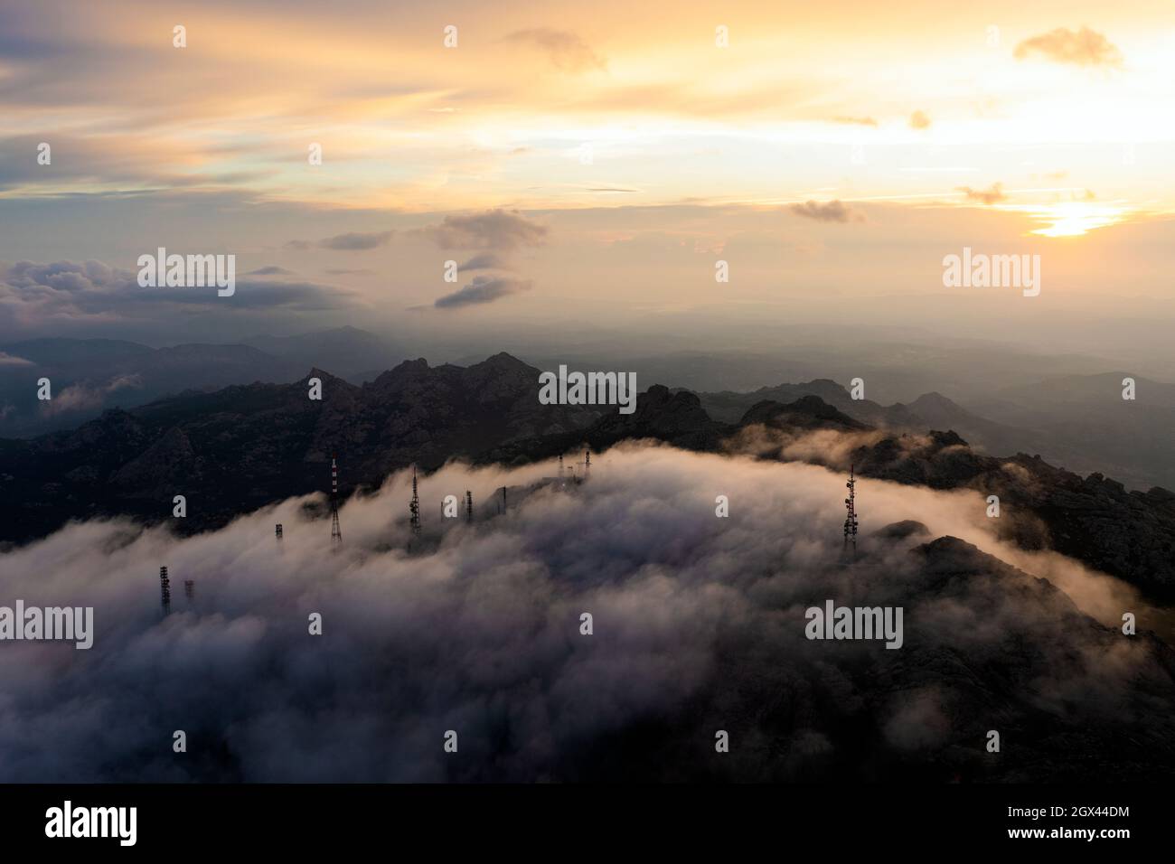Blick von oben, Luftaufnahme einer Bergkette mit einer Antennenfarm, umgeben von Wolken während eines atemberaubenden Sonnenaufgangs. Mount Limbara (Monte Limbara) Stockfoto