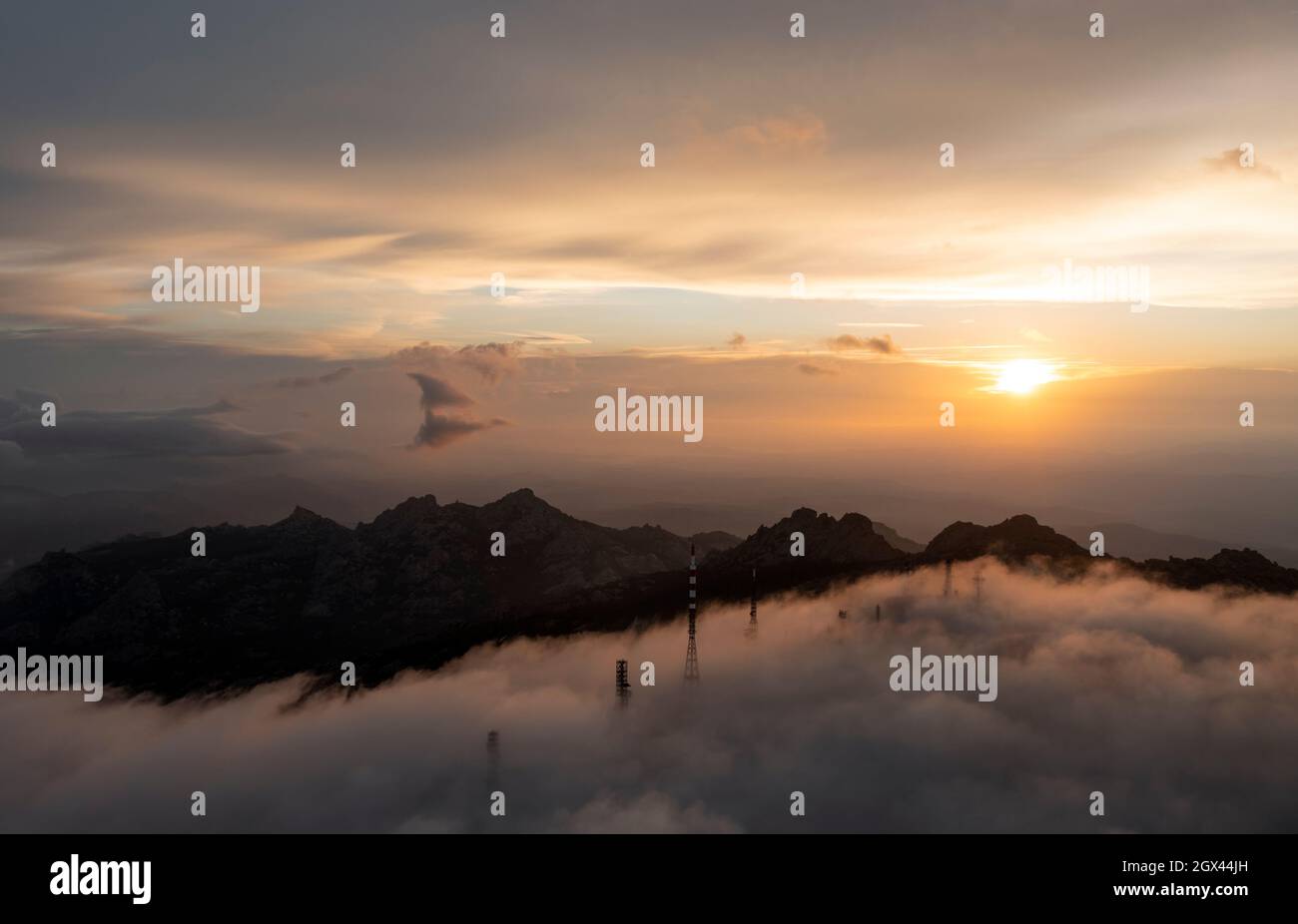 Blick von oben, Luftaufnahme einer Bergkette mit einer Antennenfarm, umgeben von Wolken während eines atemberaubenden Sonnenaufgangs. Mount Limbara (Monte Limbara) Stockfoto