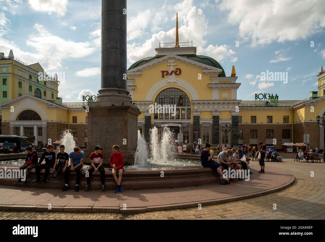 An einem sonnigen Sommertag ruhen sich die Menschen am Brunnen auf dem Bahnhofsplatz vor dem Hauptbahnhof der Stadt aus. Stockfoto