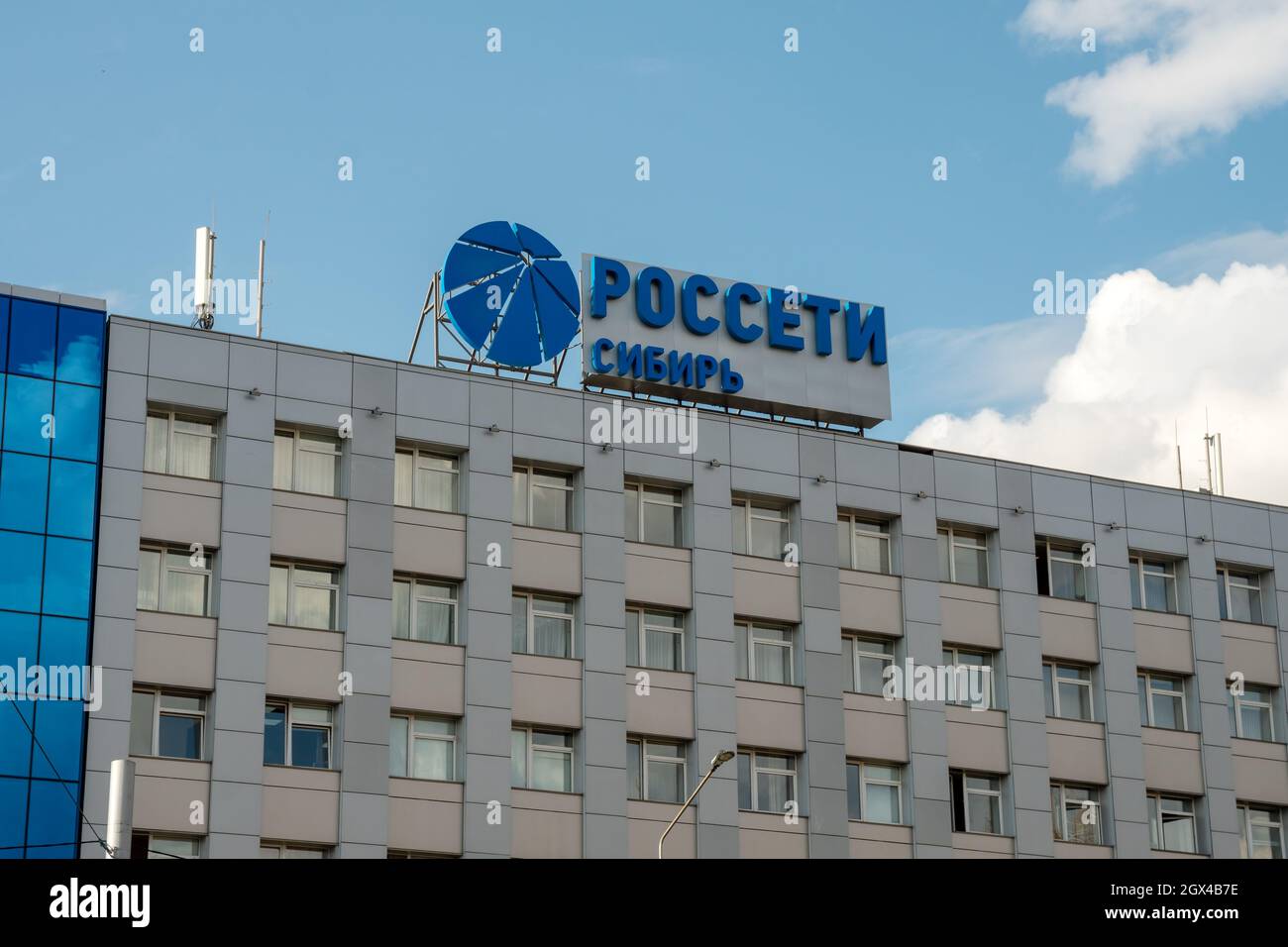 Das Logo und der Name in russischer Sprache des Unternehmens - Rosseti Sibirien - Durchführung der Übertragung und Verteilung der elektrischen Energie auf dem Dach Stockfoto