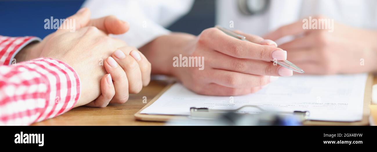Der Arzt sieht den Patienten und schreibt medizinische Indikatoren auf die Karte Stockfoto