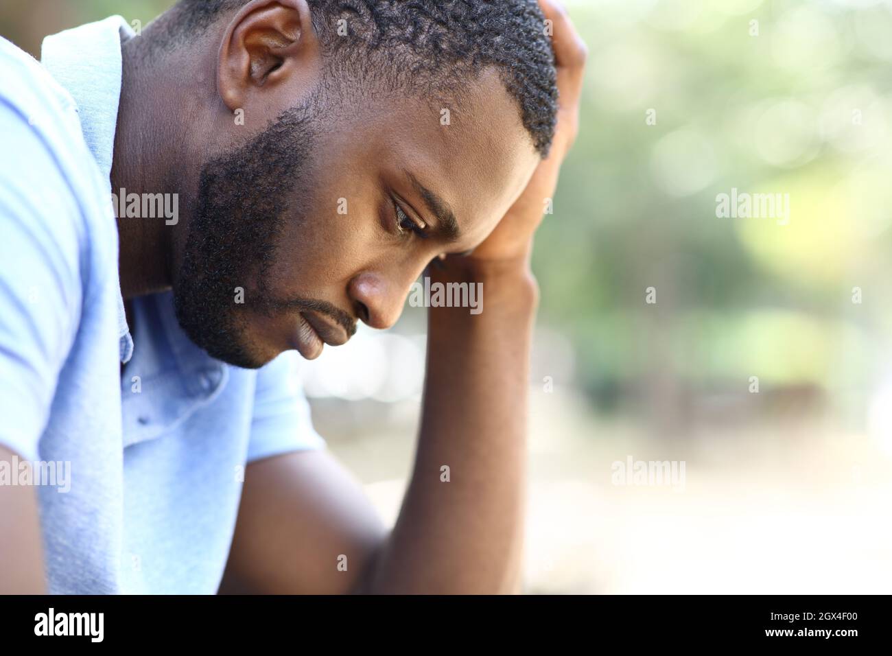 Profil eines besorgten schwarzen Mannes, der sich allein in einem Park beschwert Stockfoto