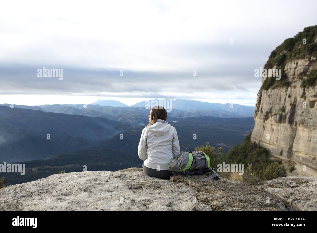 Rückansicht Porträt eines Trekkers, der auf einer Klippe sitzt und kontempliert Stockfoto