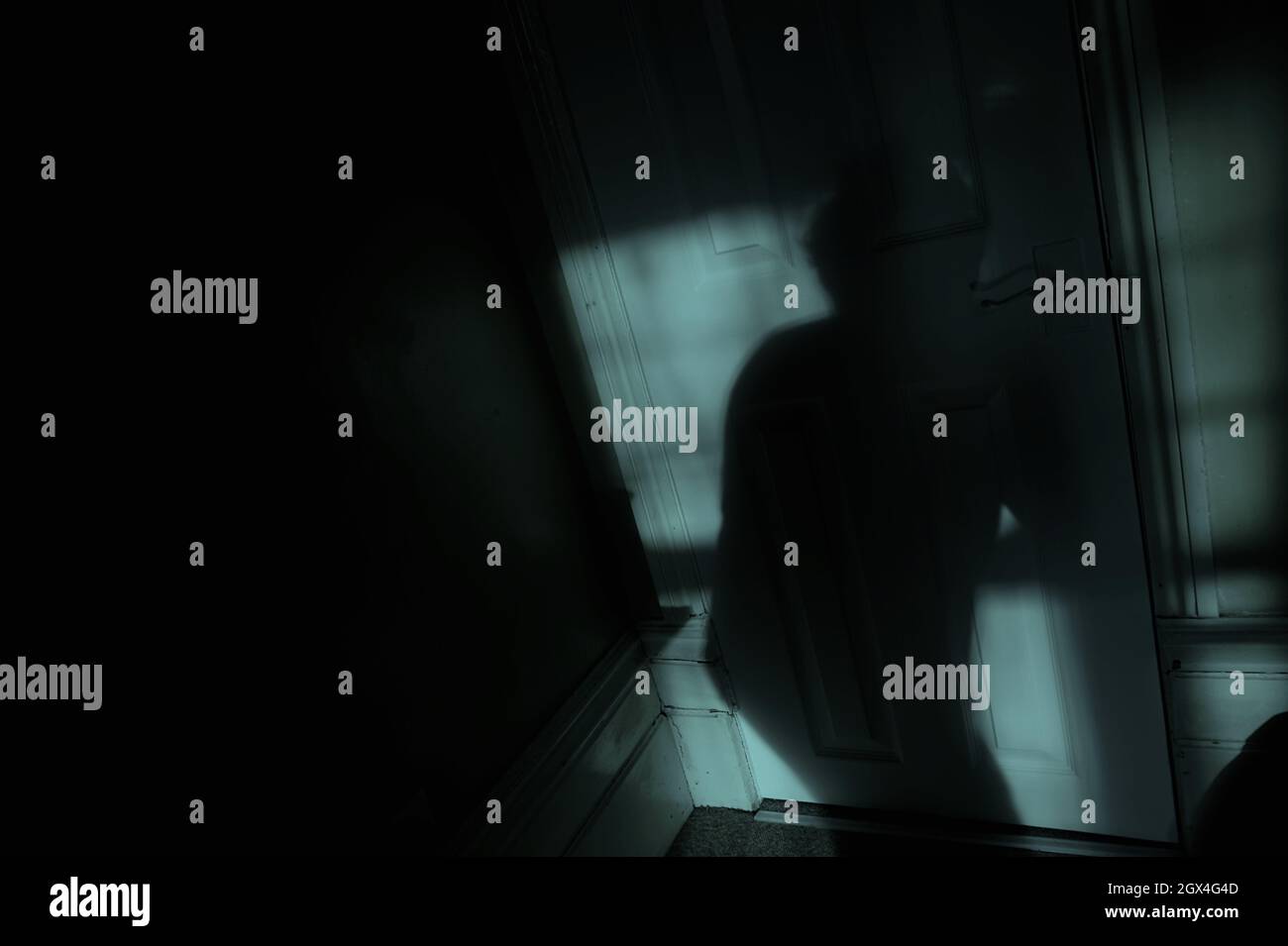 Eine schleichende Schattenfigur bewegt sich nachts durch einen mondbeleuchteten Raum Stockfoto