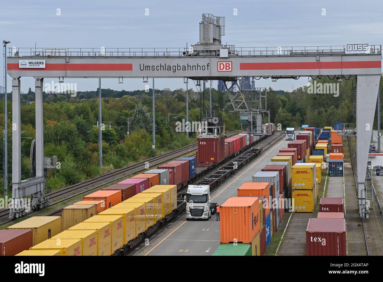 04. Oktober 2021, Brandenburg, Großbeeren: An einer Verladestation am DUSS-Terminal werden Container von der Straße auf die Schiene oder umgekehrt verladen. Der Logistikkonzern Deutsche Post DHL Group und die Deutsche Bahn AG bauen ihre bestehende Zusammenarbeit im Bereich des Paketverkehrs auf der Schiene aus. Damit soll der Anteil der per Bahn transportierten DHL-Pakete von 2 auf 6 Prozent steigen. Neue Strecken sollen auch dem bestehenden Schienennetz für Pakete hinzugefügt werden. Foto: Patrick Pleul/dpa-Zentralbild/ZB Stockfoto