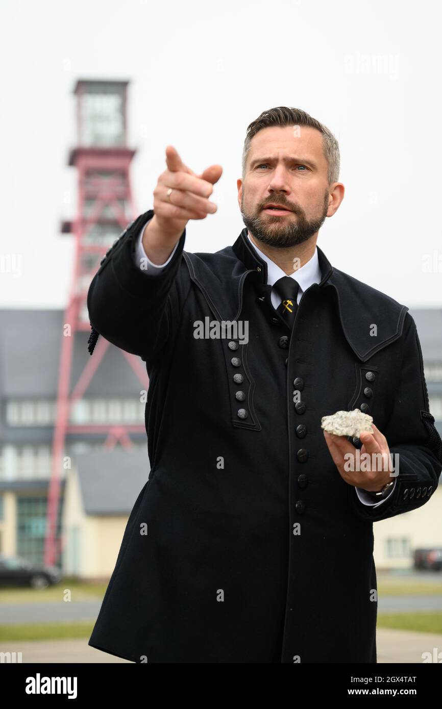 04. Oktober 2021, Sachsen, Altenberg: Der sächsische Wirtschaftsminister Martin Durig (SPD) steht während des "Rohstofftages" in einem Bergarbeiterkostüm vor dem Arno-Lippmann-Schacht und hält ein Stück mit Lithium durstigen Erz. Um sich einen Eindruck von Sachsens Anteil an der zukünftigen Rohstoffgewinnung zu verschaffen, besucht der Wirtschaftsminister verschiedene Akteure. Foto: Robert Michael/dpa Stockfoto