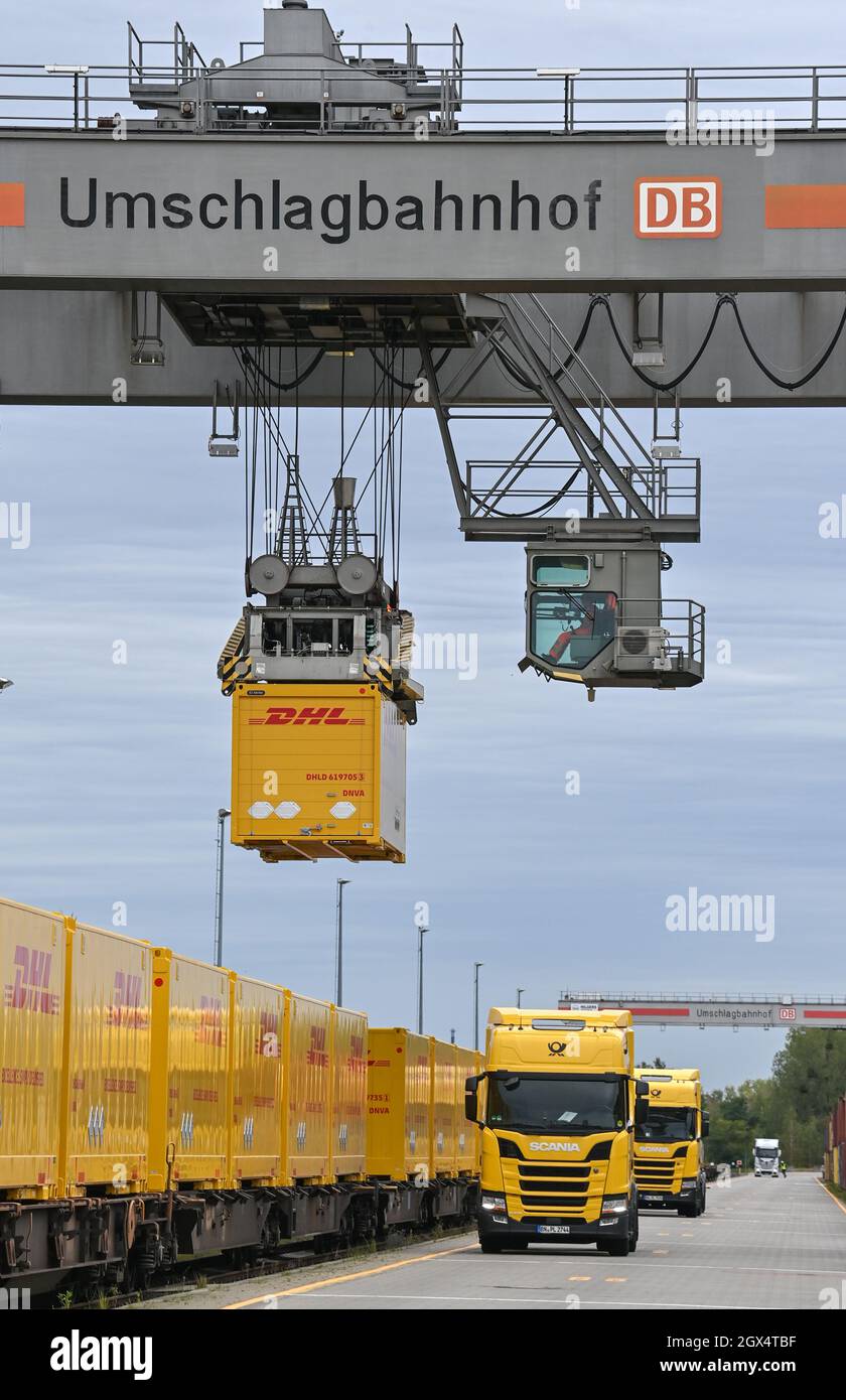 04. Oktober 2021, Brandenburg, Großbeeren: An einer Verladestation am DUSS-Terminal wird ein DHL-Container der Deutschen Post von einem LKW auf einen Wagen der Deutschen Bahn gehoben. Der Logistikkonzern Deutsche Post DHL Group und die Deutsche Bahn AG bauen ihre bestehende Zusammenarbeit im Bereich des Paketverkehrs auf der Schiene aus. Damit soll der Anteil der per Bahn transportierten DHL-Pakete von 2 auf 6 Prozent steigen. Neue Strecken sollen auch dem bestehenden Schienennetz für Pakete hinzugefügt werden. Foto: Patrick Pleul/dpa-Zentralbild/dpa Stockfoto