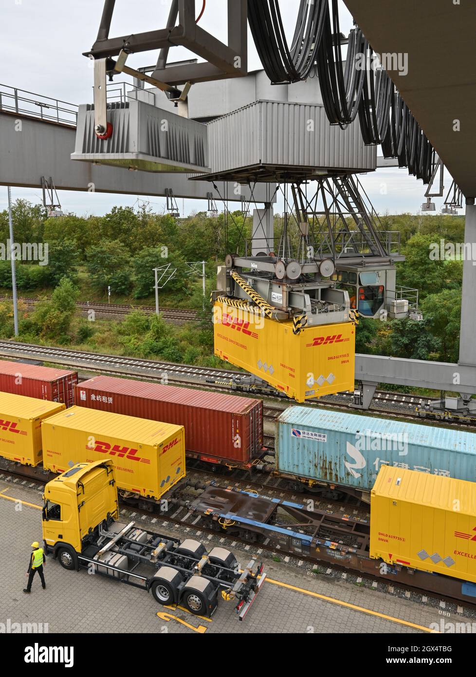 04. Oktober 2021, Brandenburg, Großbeeren: An einer Verladestation am DUSS-Terminal wird ein DHL-Container der Deutschen Post von einem LKW auf einen Wagen der Deutschen Bahn gehoben. Der Logistikkonzern Deutsche Post DHL Group und die Deutsche Bahn AG bauen ihre bestehende Zusammenarbeit im Bereich des Paketverkehrs auf der Schiene aus. Damit soll der Anteil der per Bahn transportierten DHL-Pakete von 2 auf 6 Prozent steigen. Neue Strecken sollen auch dem bestehenden Schienennetz für Pakete hinzugefügt werden. Foto: Patrick Pleul/dpa-Zentralbild/dpa Stockfoto