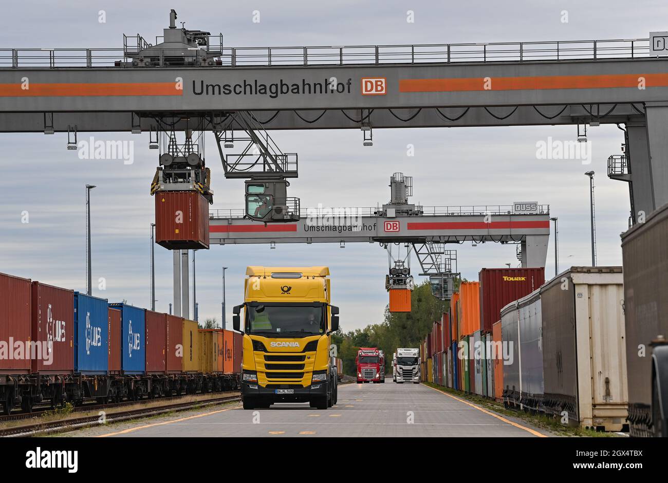 04. Oktober 2021, Brandenburg, Großbeeren: An einer Verladestation am DUSS-Terminal werden Container von der Straße auf die Schiene oder umgekehrt verladen. Der Logistikkonzern Deutsche Post DHL Group und die Deutsche Bahn AG bauen ihre bestehende Zusammenarbeit im Bereich des Paketverkehrs auf der Schiene aus. Damit soll der Anteil der per Bahn transportierten DHL-Pakete von 2 auf 6 Prozent steigen. Neue Strecken sollen auch dem bestehenden Schienennetz für Pakete hinzugefügt werden. Foto: Patrick Pleul/dpa-Zentralbild/dpa Stockfoto