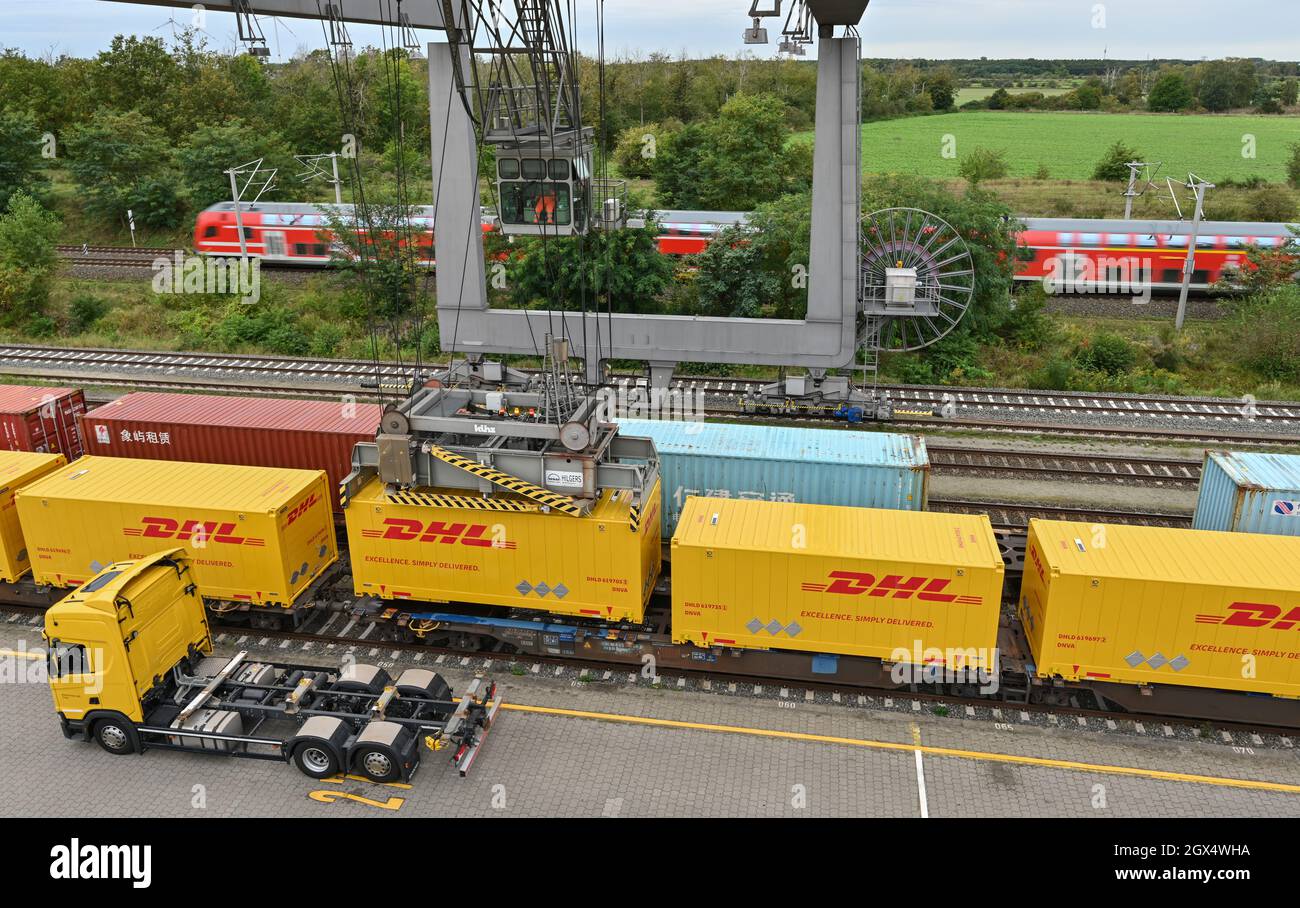 04. Oktober 2021, Brandenburg, Großbeeren: An einer Verladestation am DUSS-Terminal wird ein DHL-Container der Deutschen Post von einem LKW auf einen Wagen der Deutschen Bahn gehoben. Der Logistikkonzern Deutsche Post DHL Group und die Deutsche Bahn AG bauen ihre bestehende Zusammenarbeit im Bereich des Paketverkehrs auf der Schiene aus. Damit soll der Anteil der per Bahn transportierten DHL-Pakete von 2 auf 6 Prozent steigen. Neue Strecken sollen auch dem bestehenden Schienennetz für Pakete hinzugefügt werden. Foto: Patrick Pleul/dpa-Zentralbild/dpa Stockfoto