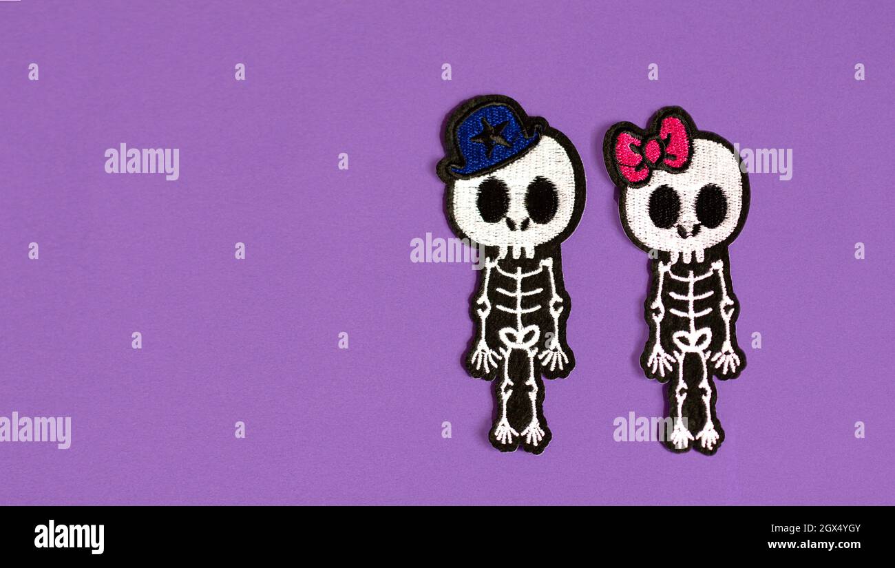 Skelette eines Jungen und eines Mädchens auf purpurem Hintergrund, das Konzept von Halloween und der Tag des toten mexikanischen Feiertags Stockfoto