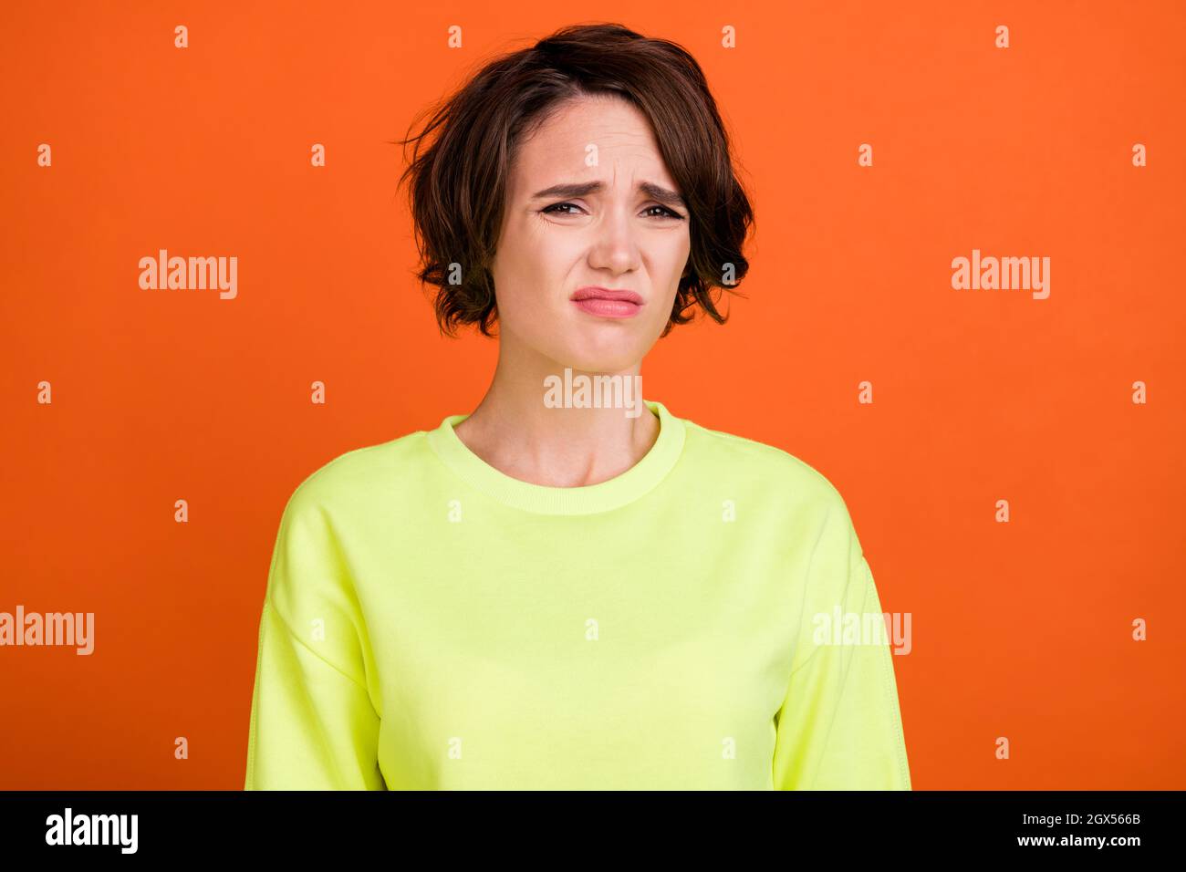Foto von jungen braunen bob behaart unglücklich gestresst Frau schlechte Stimmung Grimasse isoliert auf orangen Hintergrund Stockfoto