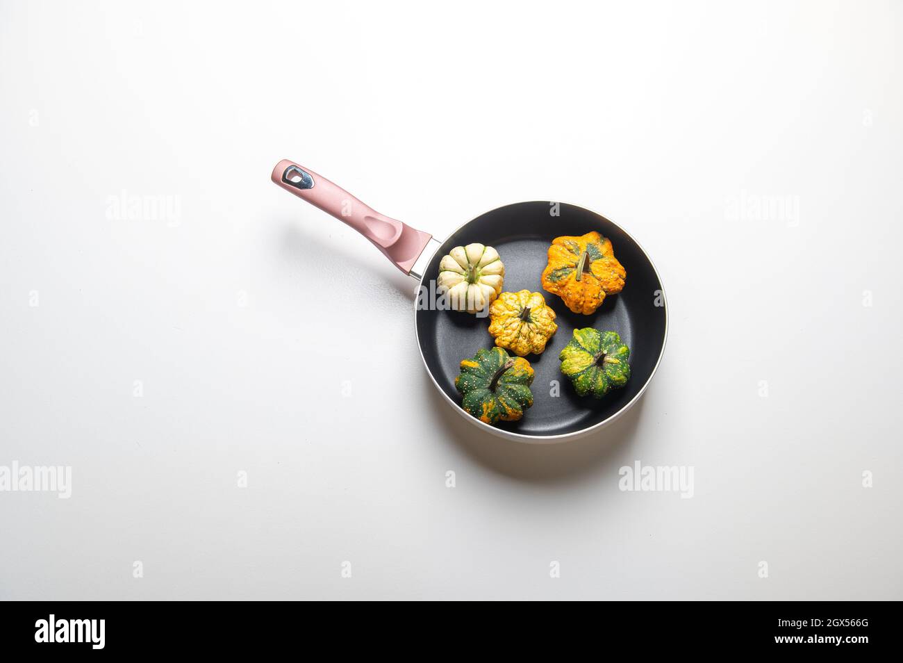 Dekorative Kürbisse auf einer Pfanne über einem weißen Küchentisch Hintergrund.Konzept von Thanksgiving Day, Halloween oder Herbsternte. Stockfoto