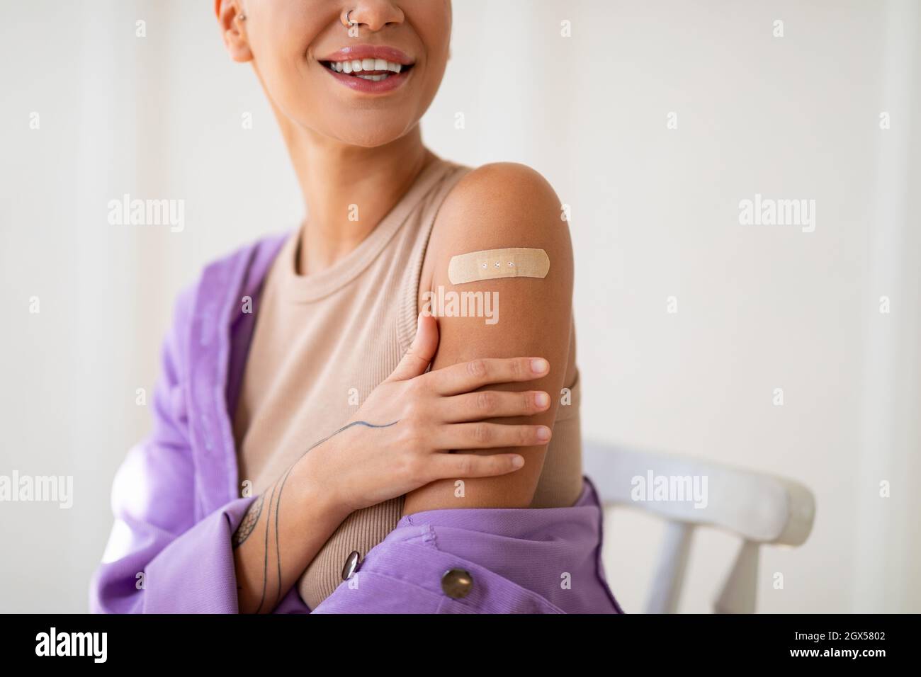 Erfolgreiche Covid-19-Impfung. Glückliche junge Dame, die nach der Injektion des Coronavirus-Impfstoffs den Arm mit Gips zeigt Stockfoto