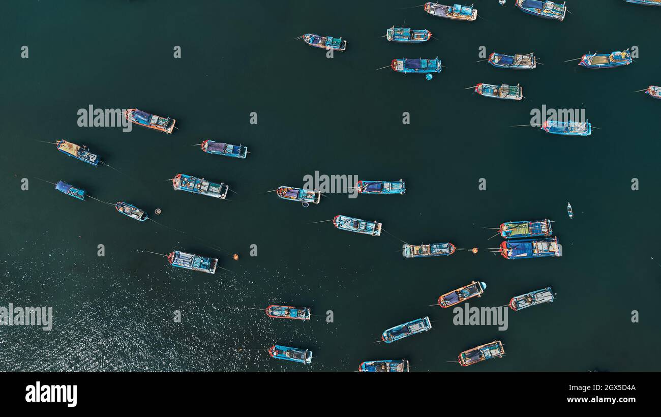 Viele farbige Fischerboote im Meer zwischen den blau-grünen Gewässern. Luftaufnahme von der Drohne. Nha Trang, Vietnam Stockfoto