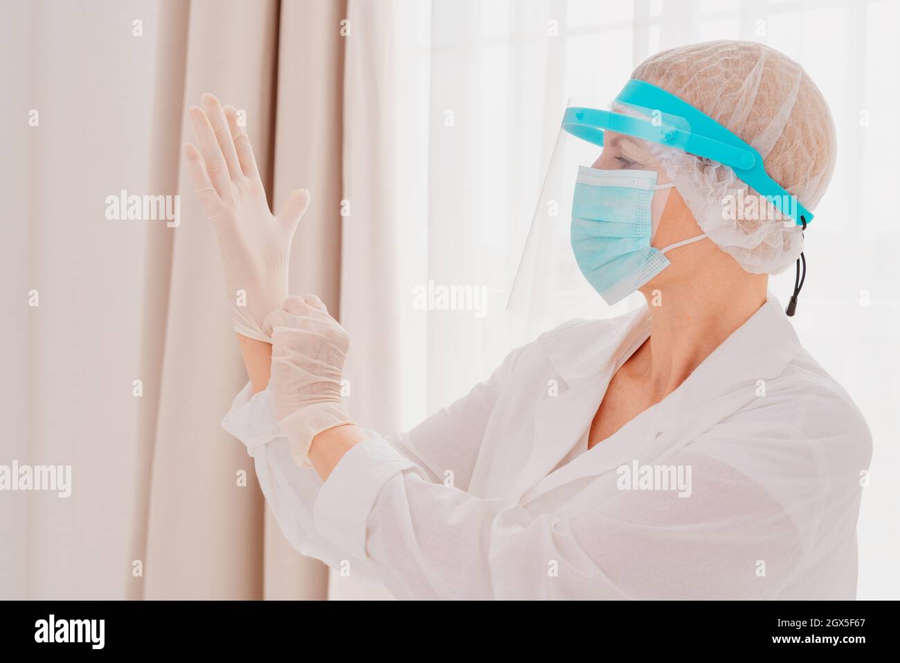 Der Arzt passt die Handschuhe an, um sich vor dem Covid-19-Virus zu schützen Stockfoto