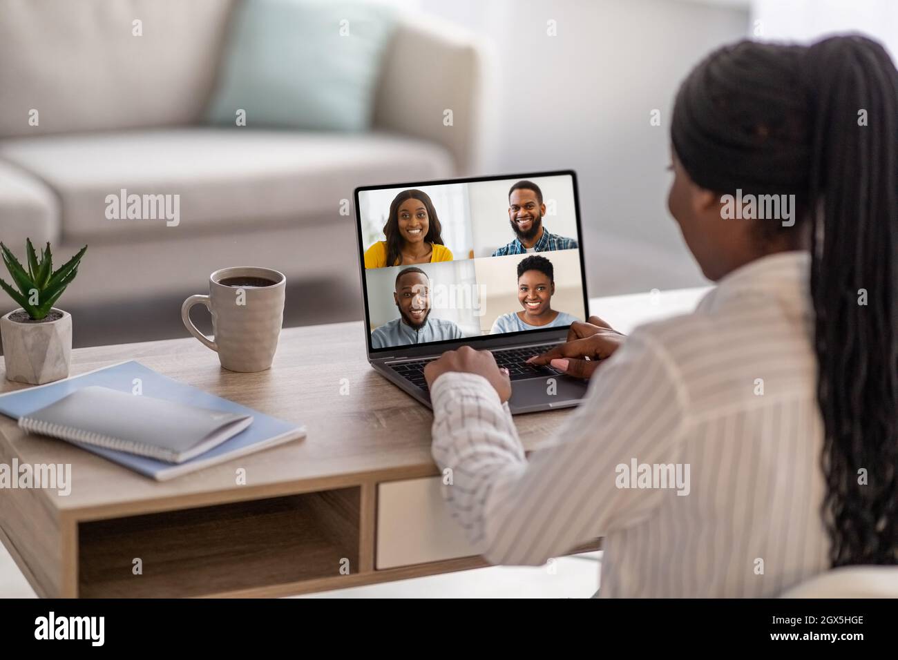 Junge afroamerikanische Dame hat Videoanruf, trifft sich mit Studenten bei der Vorlesung oder Webinar auf dem Computerbildschirm am Arbeitsplatz Stockfoto