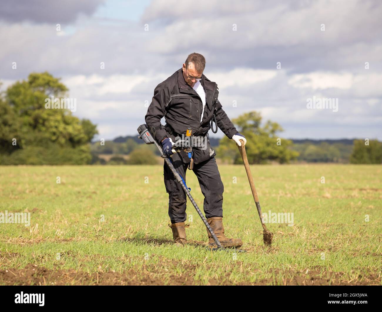 Schatzsucher mit einem Metalldetektor auf einem Feld. Hertfordshire, Großbritannien. Stockfoto