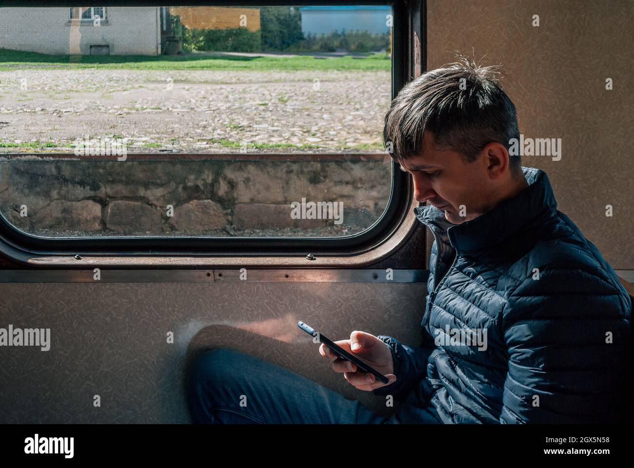 Ein Mann benutzt ein Smartphone, das im Wagen eines alten Zuges sitzt Stockfoto