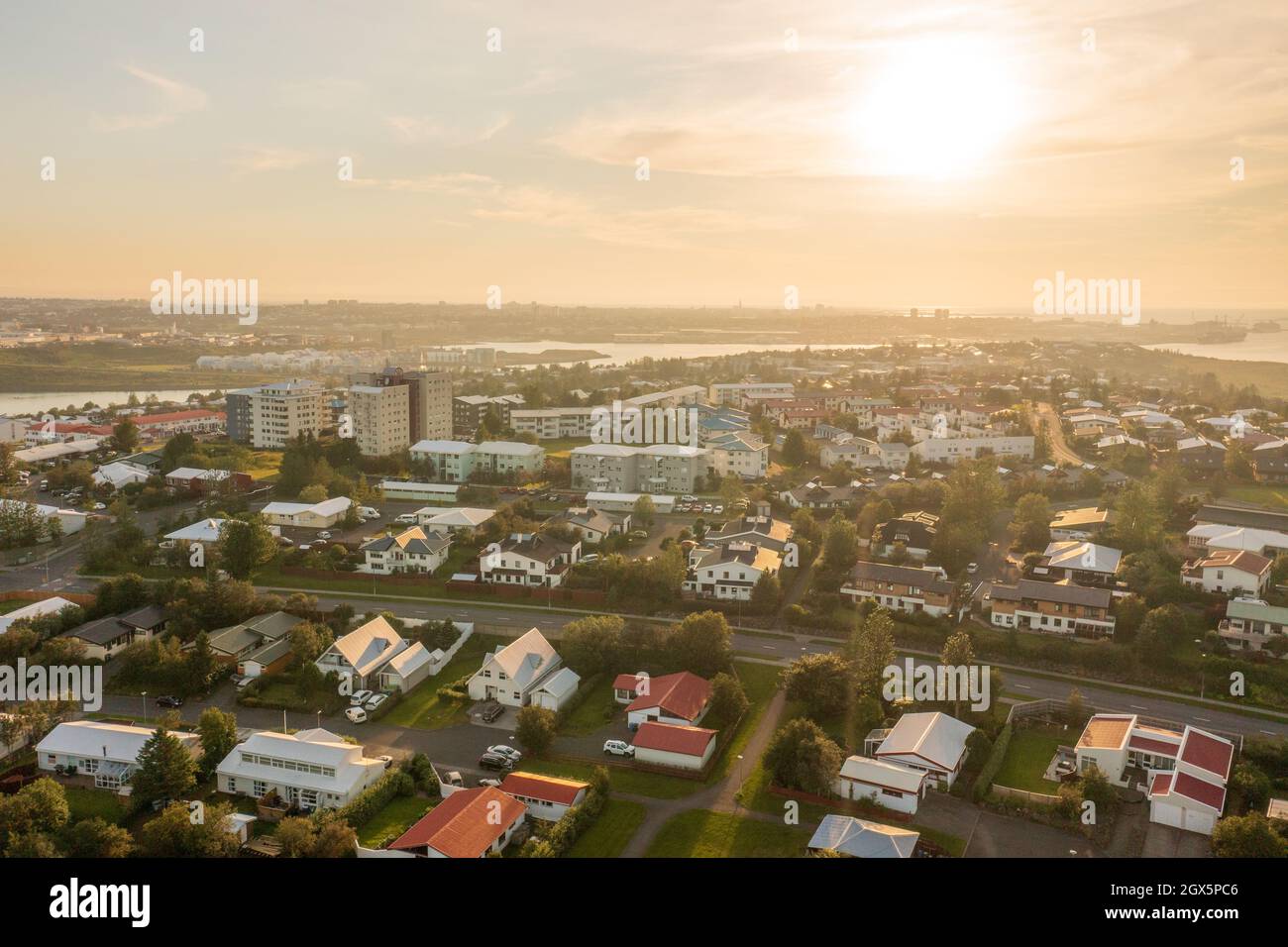 Drohnenansicht von Vorstadthäusern und Wohngebäuden auf ruhigen Straßen in der Nähe des Flusses gegen den bewölkten Morgenhimmel. Stockfoto