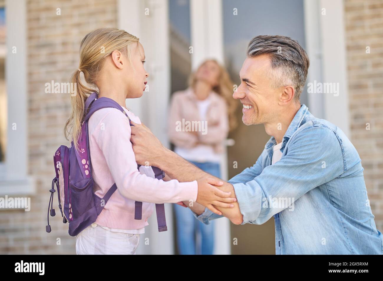 Lächelnder Mann, der sich in der Nähe seiner kleinen Tochter hockend Stockfoto