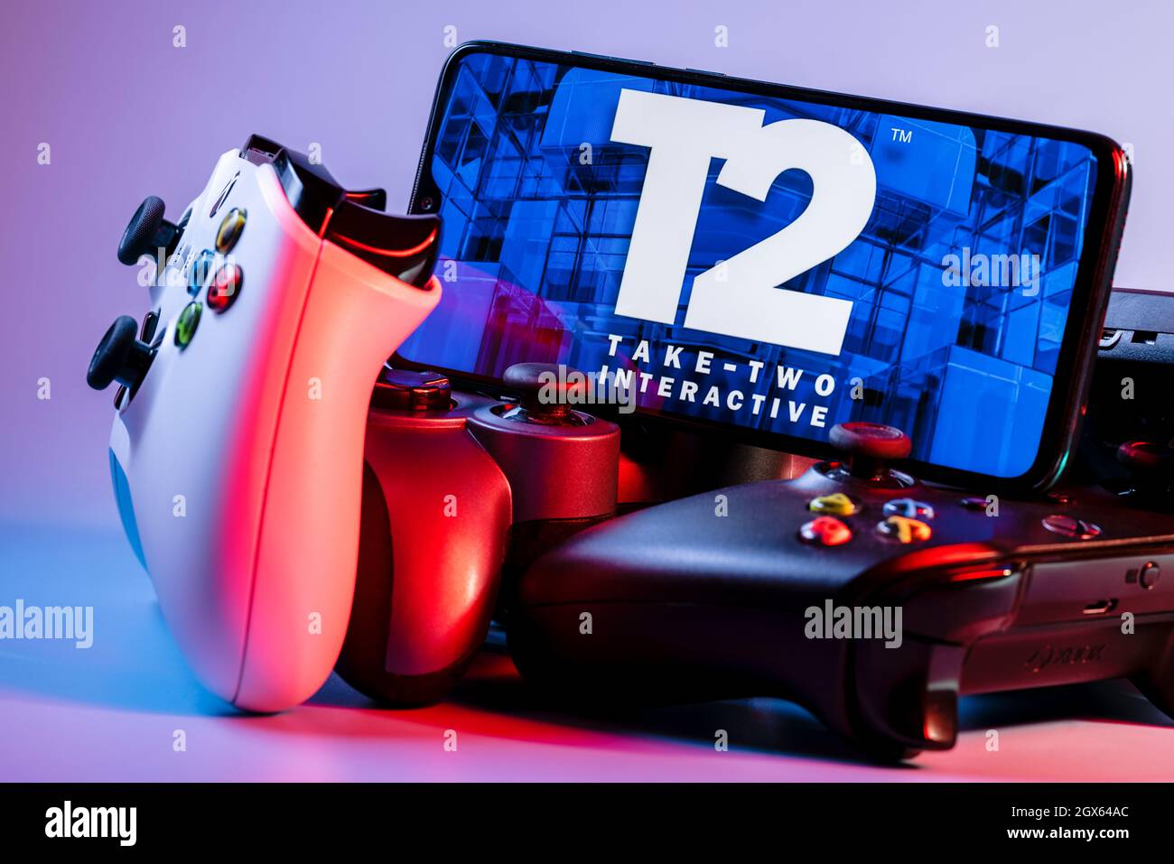 Ein Smartphone mit dem Take-Two-Logo auf dem Bildschirm auf dem Stapel der Gamepads. Stockfoto